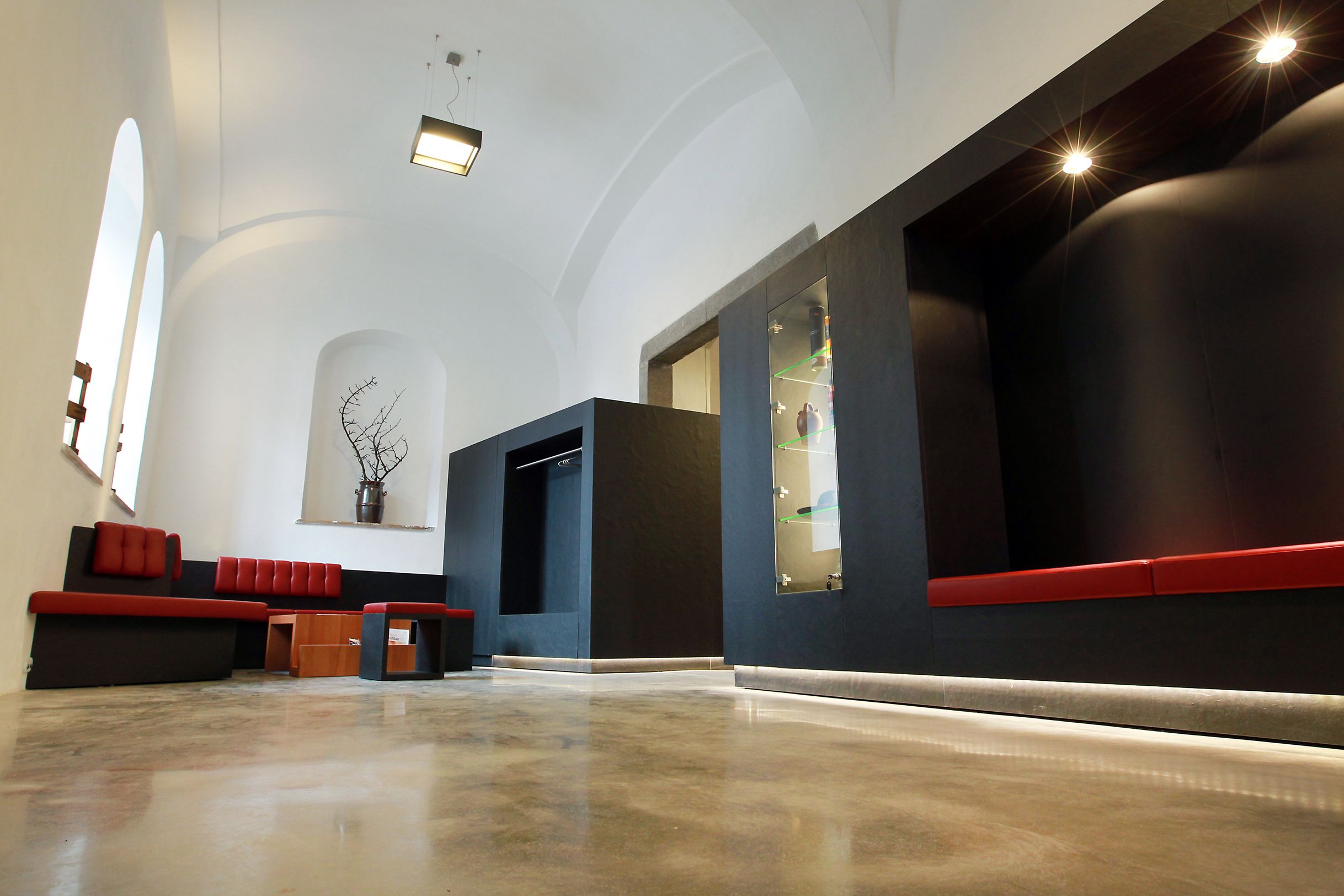 Moderner Innenraum mit roten Sitzbänken und schwarzen Wänden.
