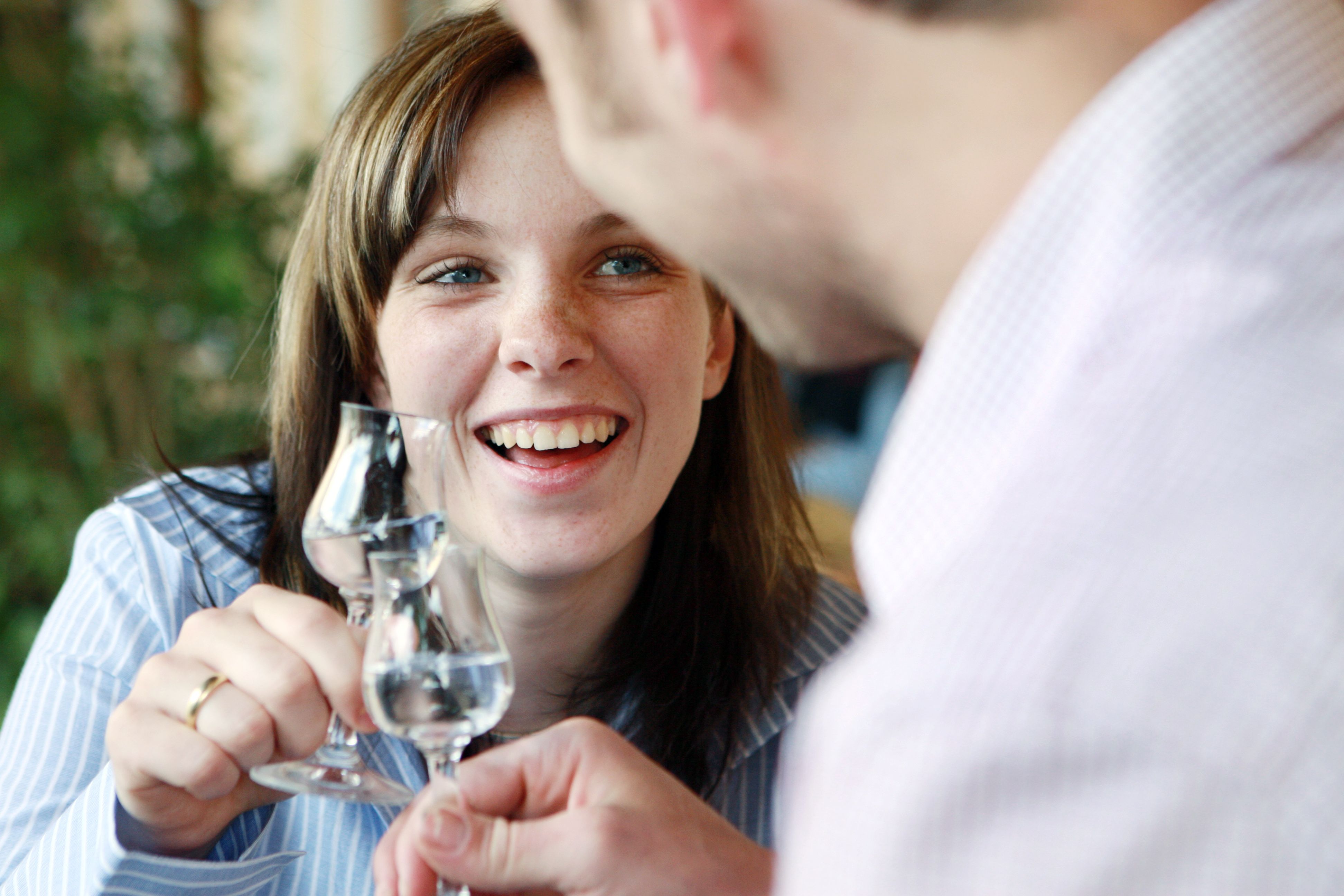 Zwei Personen stoßen mit Schnapsgläsern an und lächeln.