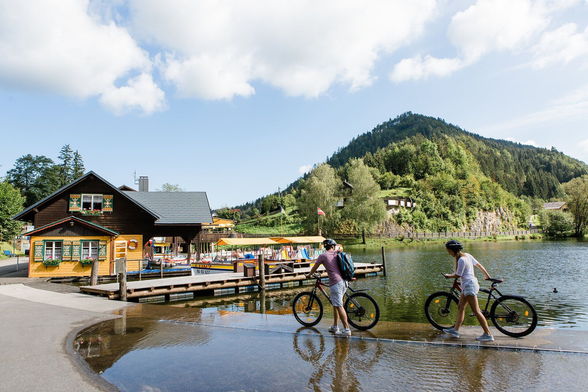 Ein malerischer Tag am Ybbstalradweg, wo Radfahrer die sanften Wellen der Landschaft genießen. Die klare Luft und das sanfte Plätschern des Wassers schaffen eine entspannende Atmosphäre, während die umliegenden Berge majestätisch in den Himmel ragen.