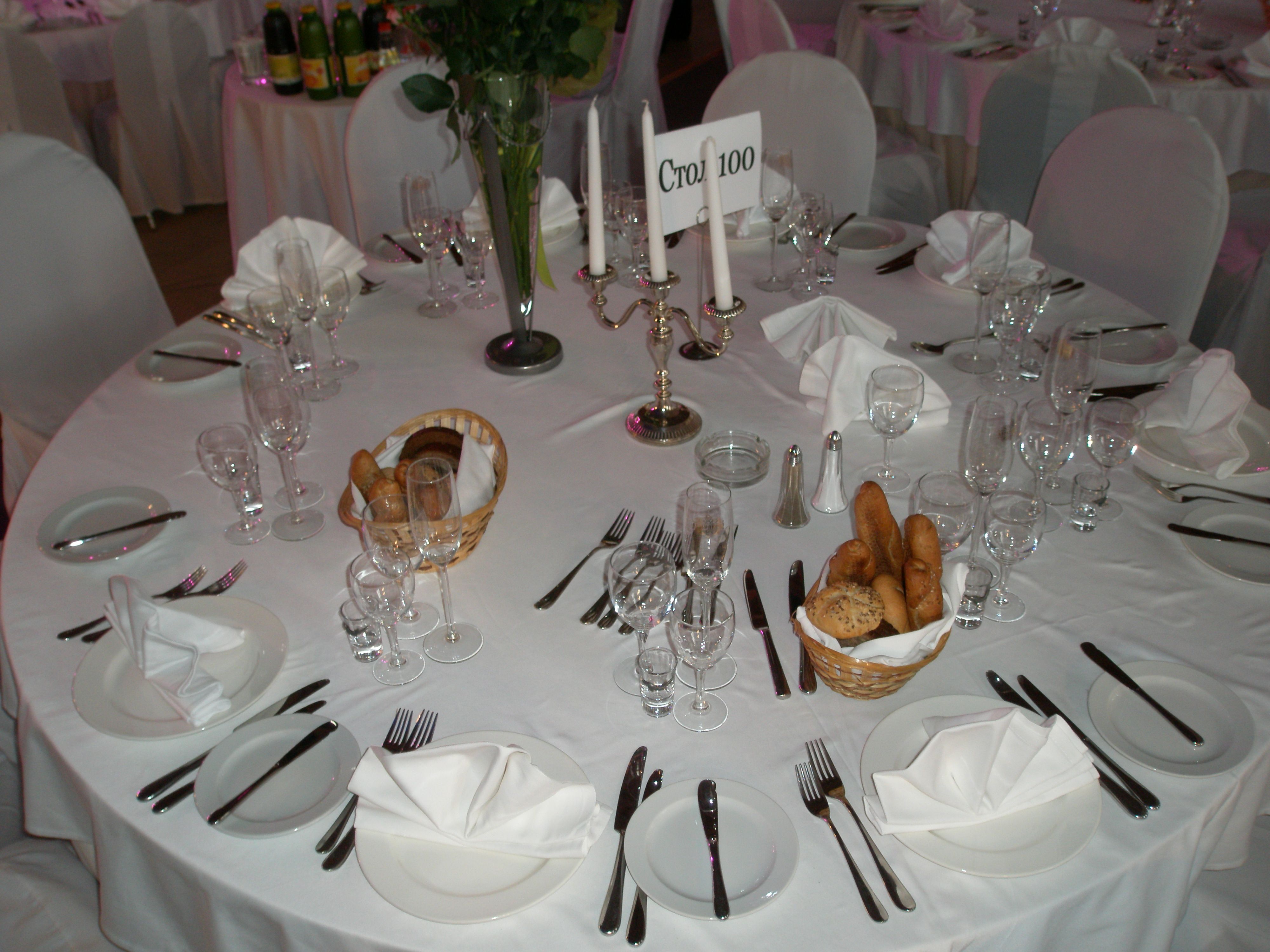 Eleganter, gedeckter Tisch mit weißen Tischdecken, Kerzenständer und Brotkörben.