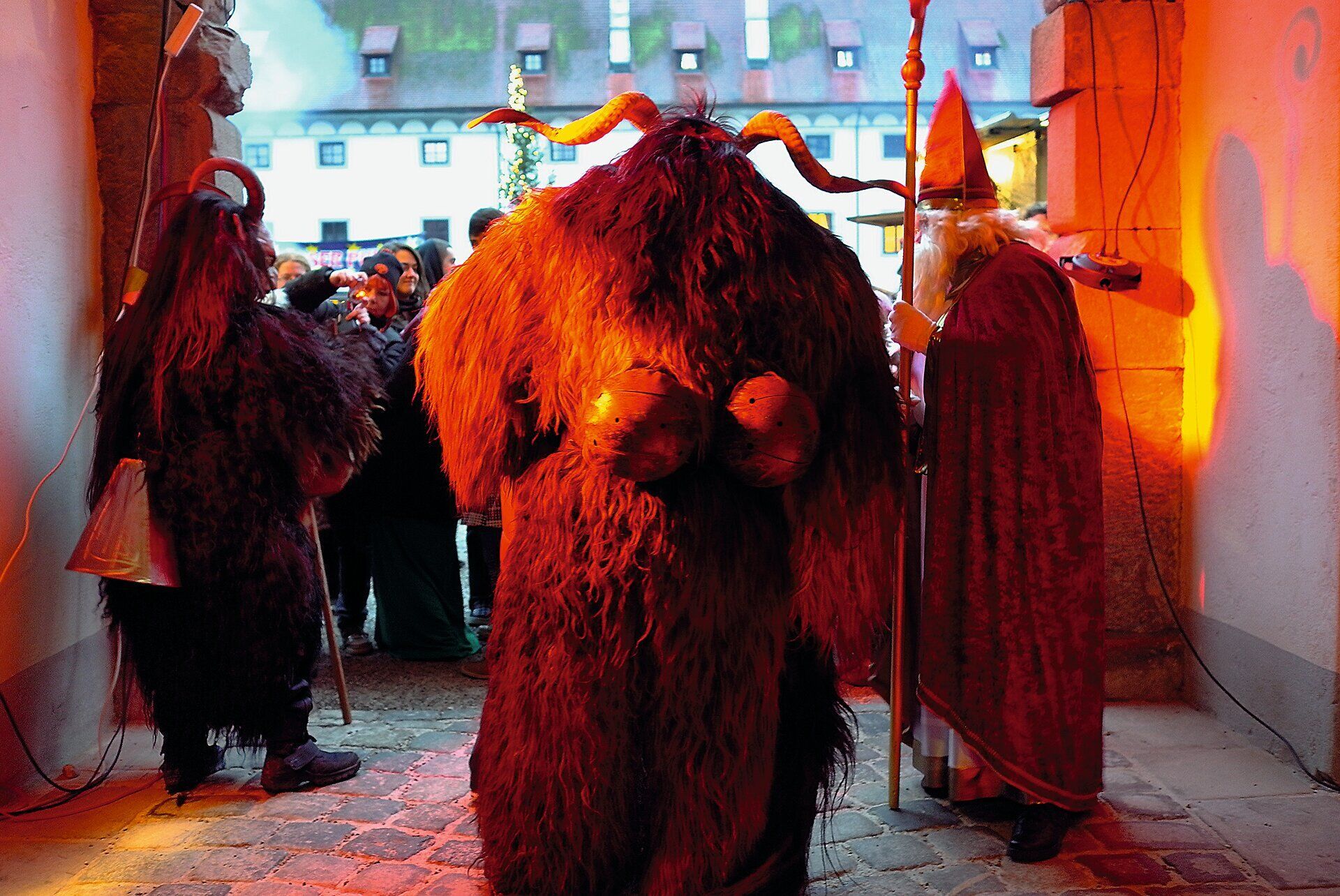 In der festlichen Atmosphäre der Kartause Gaming versammeln sich Menschen in traditionellen Kostümen, die mit lebhaften Farben und eindrucksvollen Masken die altehrwürdigen Mauern zum Leben erwecken. Die Klänge von Musik und fröhlichem Lachen erfüllen die Luft, während die Teilnehmer in einem bunten Treiben die Traditionen lebendig halten.