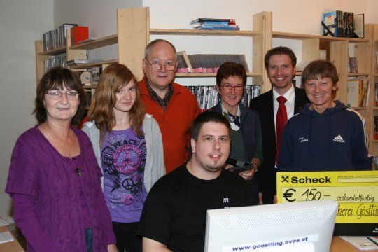 Gruppe von Menschen in einer Bücherei mit einem Scheck über 150 Euro.