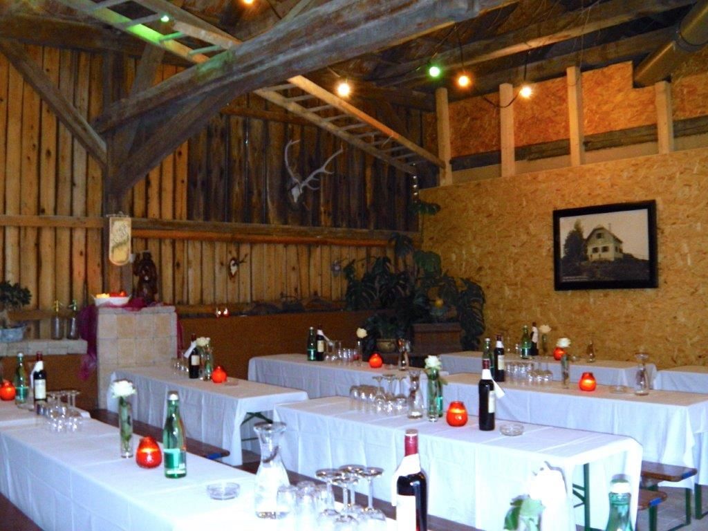 Rustikaler Veranstaltungsraum mit Holzwänden, gedeckten Tischen und Dekoration.