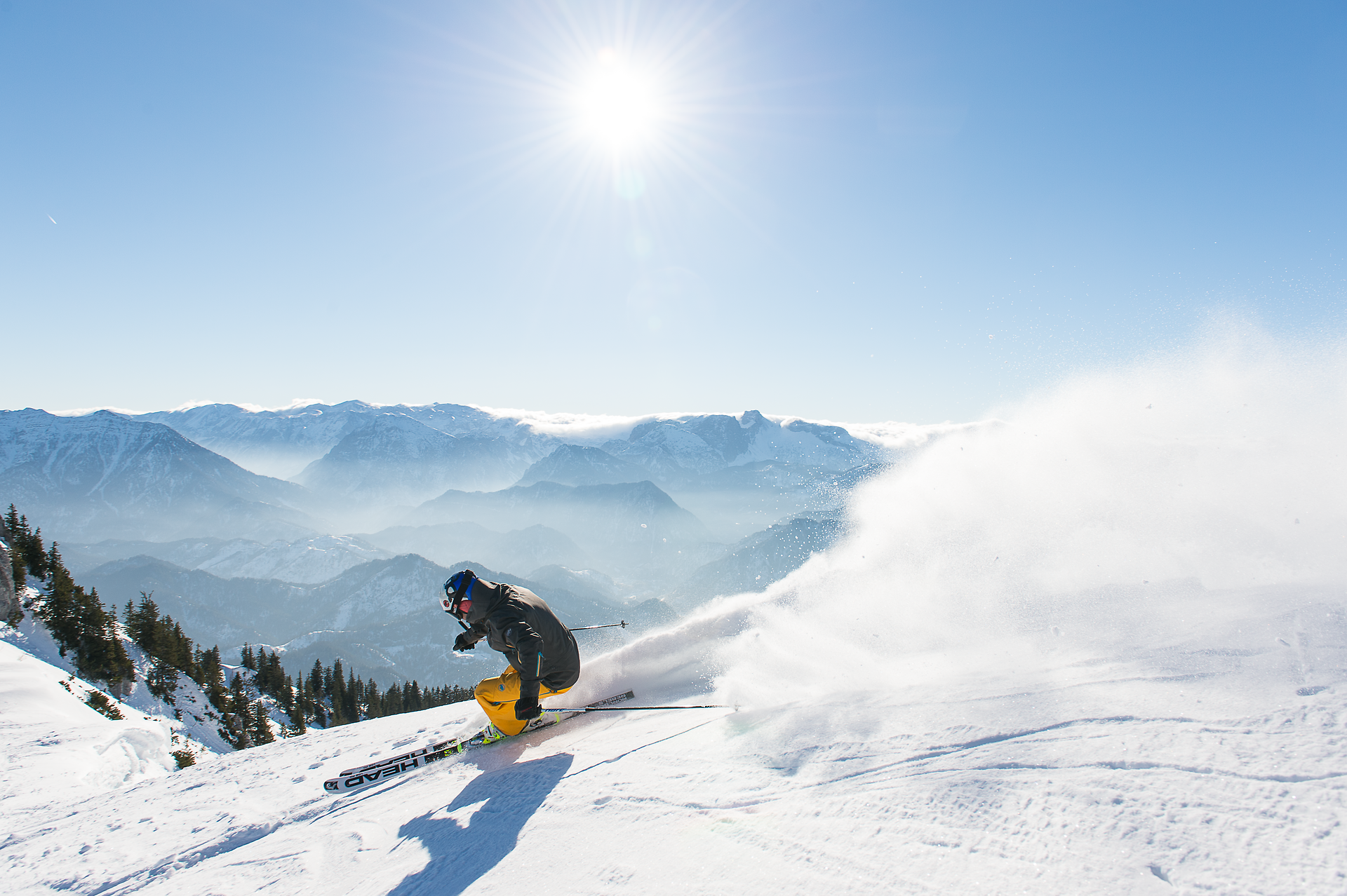 Die strahlende Sonne über den schneebedeckten Gipfeln schafft eine magische Atmosphäre, während ein Skifahrer elegant durch den frischen Pulverschnee gleitet. Die majestätische Berglandschaft lädt zu unvergesslichen Abenteuern ein und verspricht pure Freiheit in der Natur.