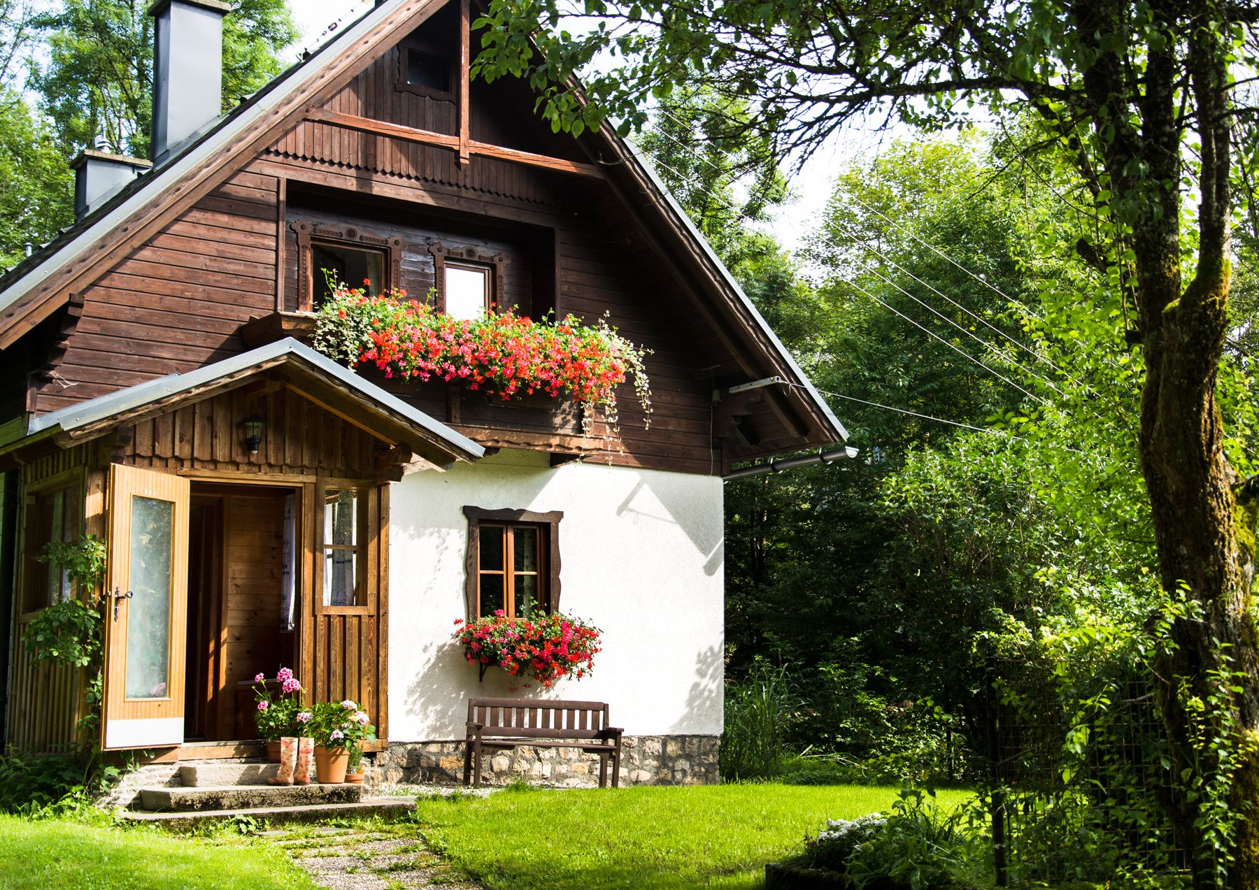 Ein malerisches Ferienhaus mit Holzverkleidung und Blumenkästen, umgeben von üppigem Grün.
