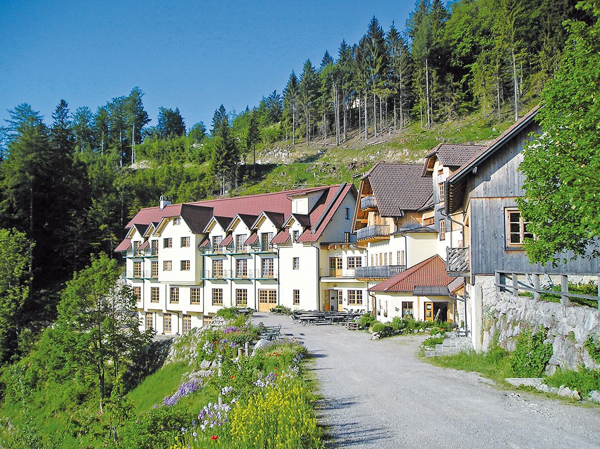 Ein großes Gebäude mit roten Dächern in einer grünen, bewaldeten Umgebung.
