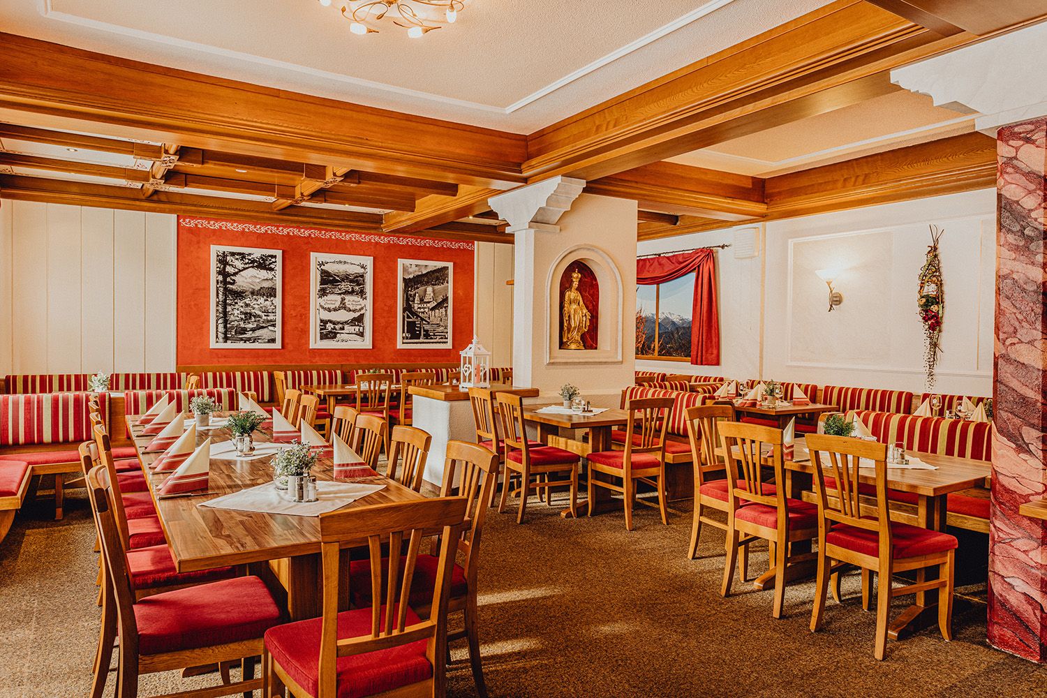 Gemütlicher Gastraum mit Holzmöbeln und rot-weiß gestreiften Polstern.