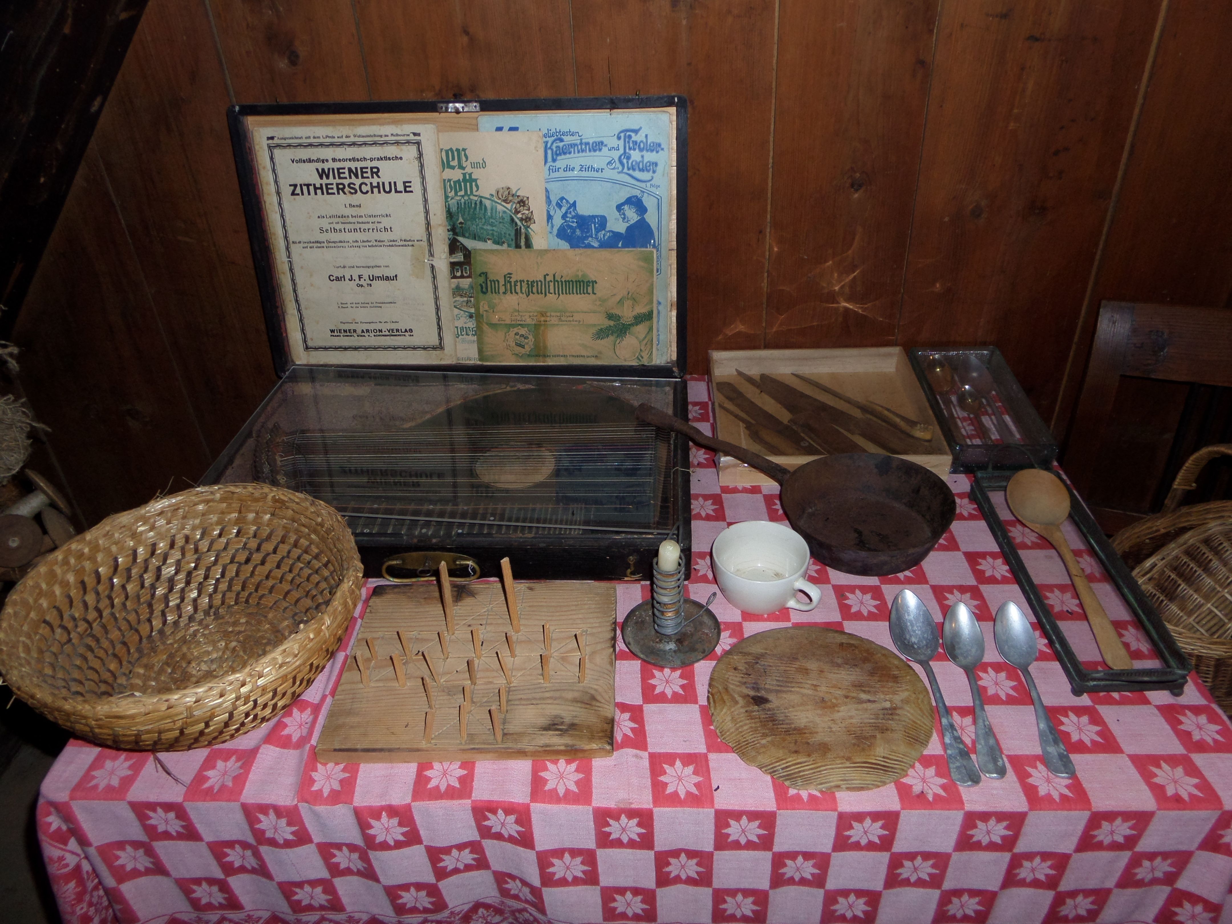 Tisch mit alten Küchenutensilien und Zitherschule-Büchern.