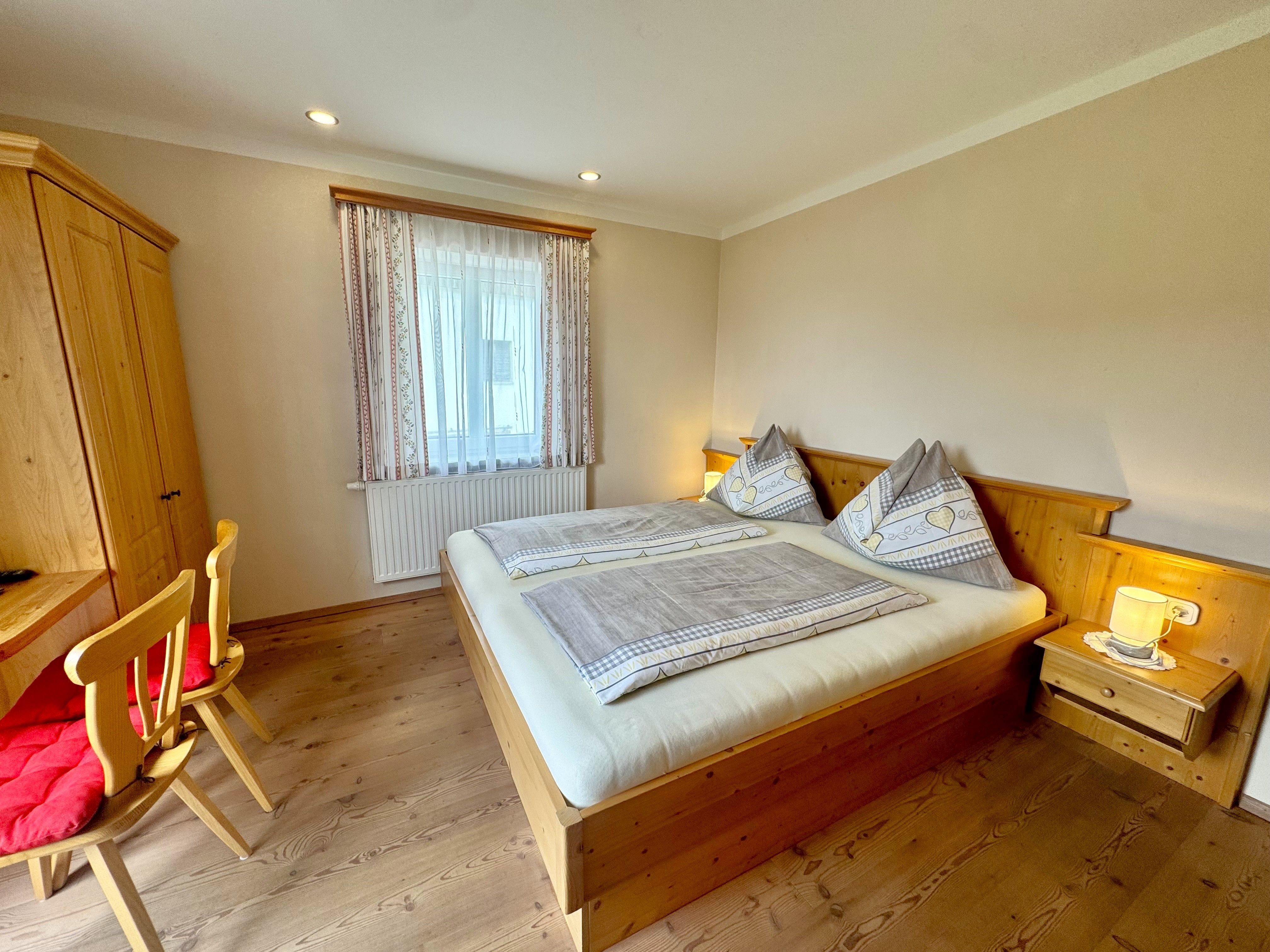 Gemütliches Schlafzimmer mit Holzmöbeln, Doppelbett und Schreibtisch.