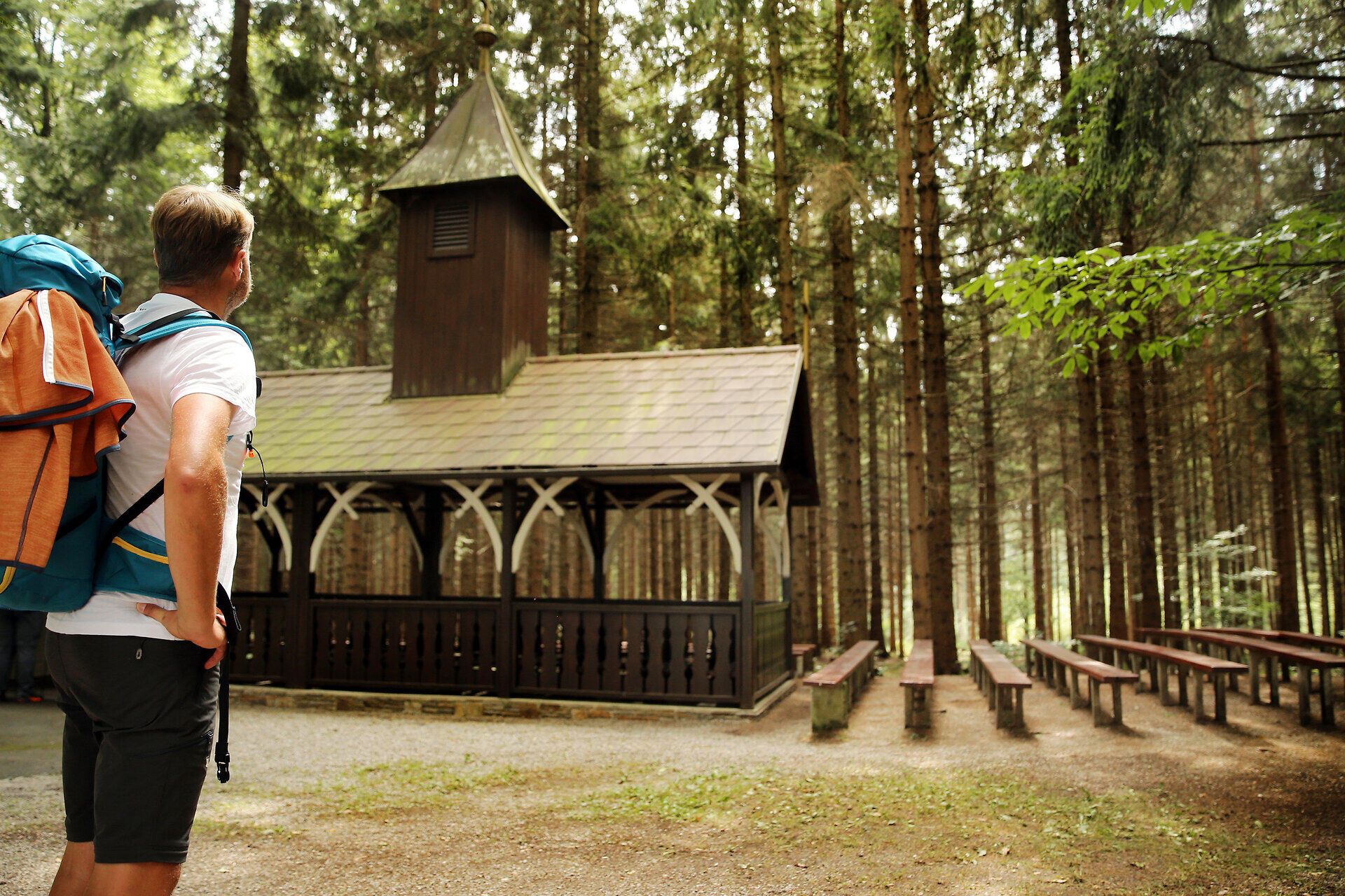 Ein Pilgerer bestaunt eine Kirche aus Holz inmitten eines Waldes.