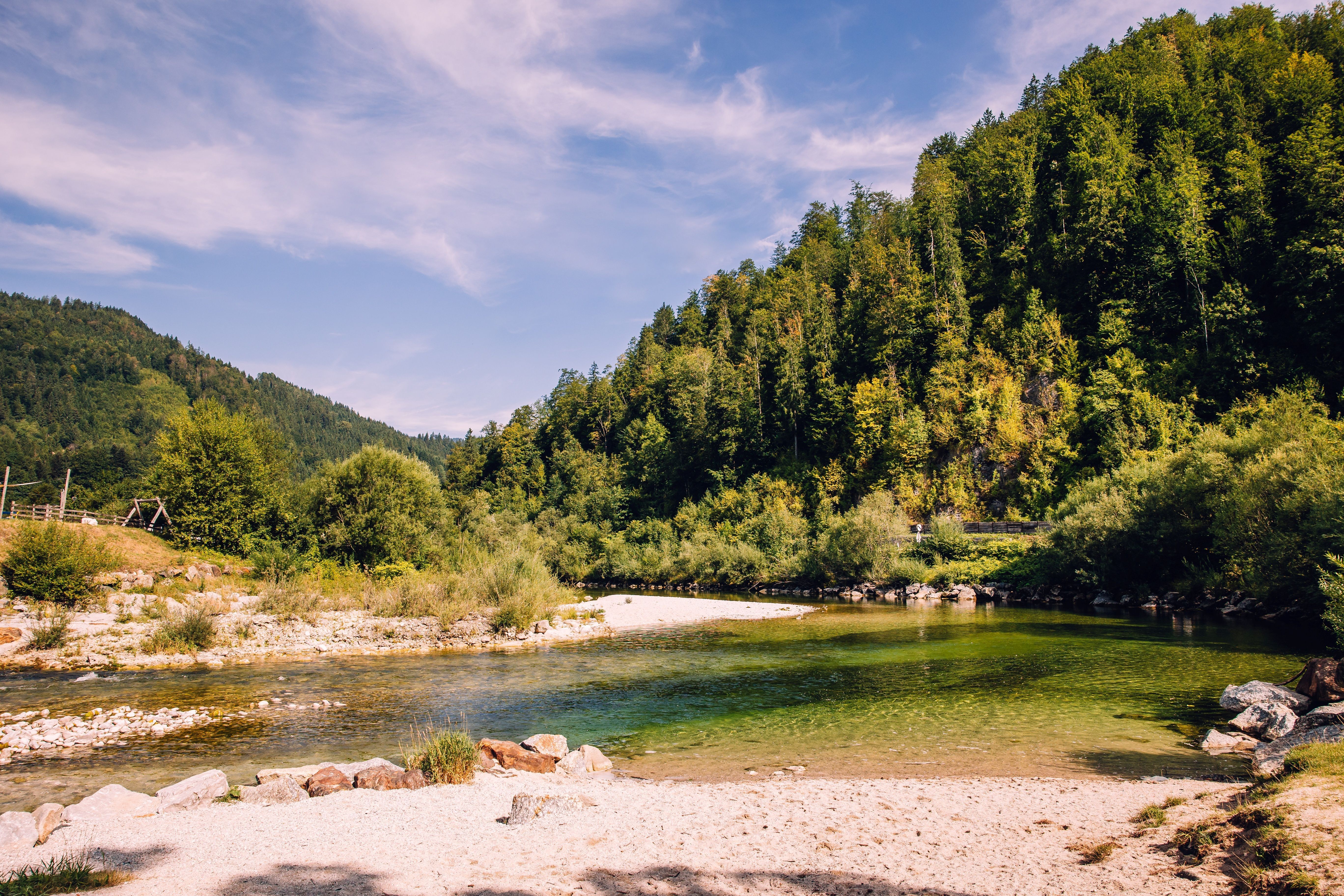 Landschaft bei Göstling: klarer Fluss mit Kiesufer, umgeben von bewaldeten Hängen unter blauem Himmel.