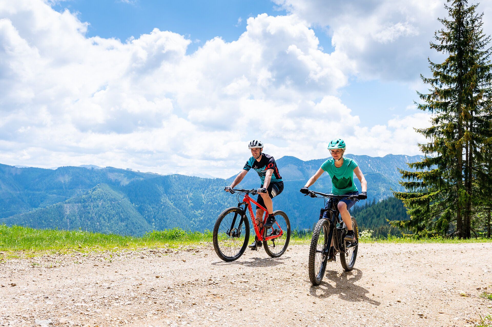 Ein Paar genießt die frische Bergluft und die atemberaubende Aussicht auf die Ybbstaler Alpen, während sie auf ihren Mountainbikes die malerischen Wege erkunden. Umgeben von saftigem Grün und majestätischen Gipfeln, erleben sie den Sommer in den Bergen in seiner schönsten Form.