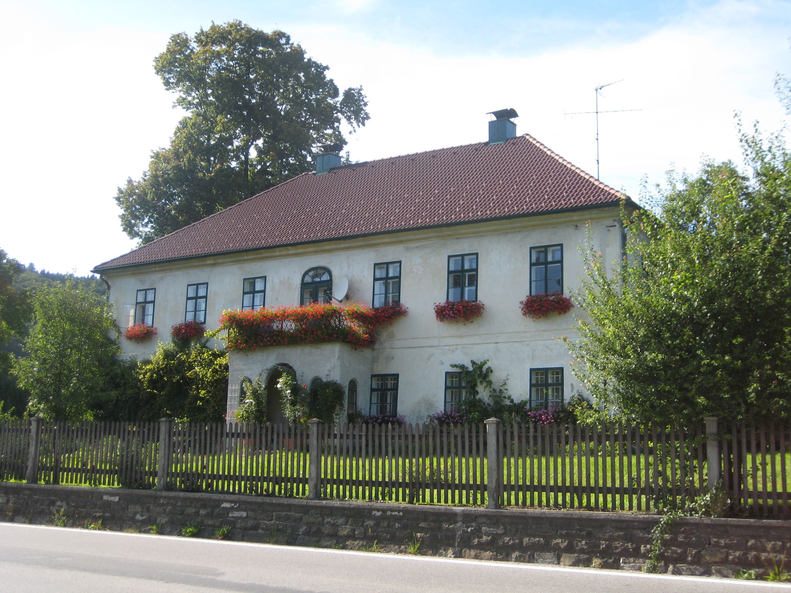Ein zweistöckiges Haus mit roten Dachziegeln und Blumenkästen an den Fenstern.