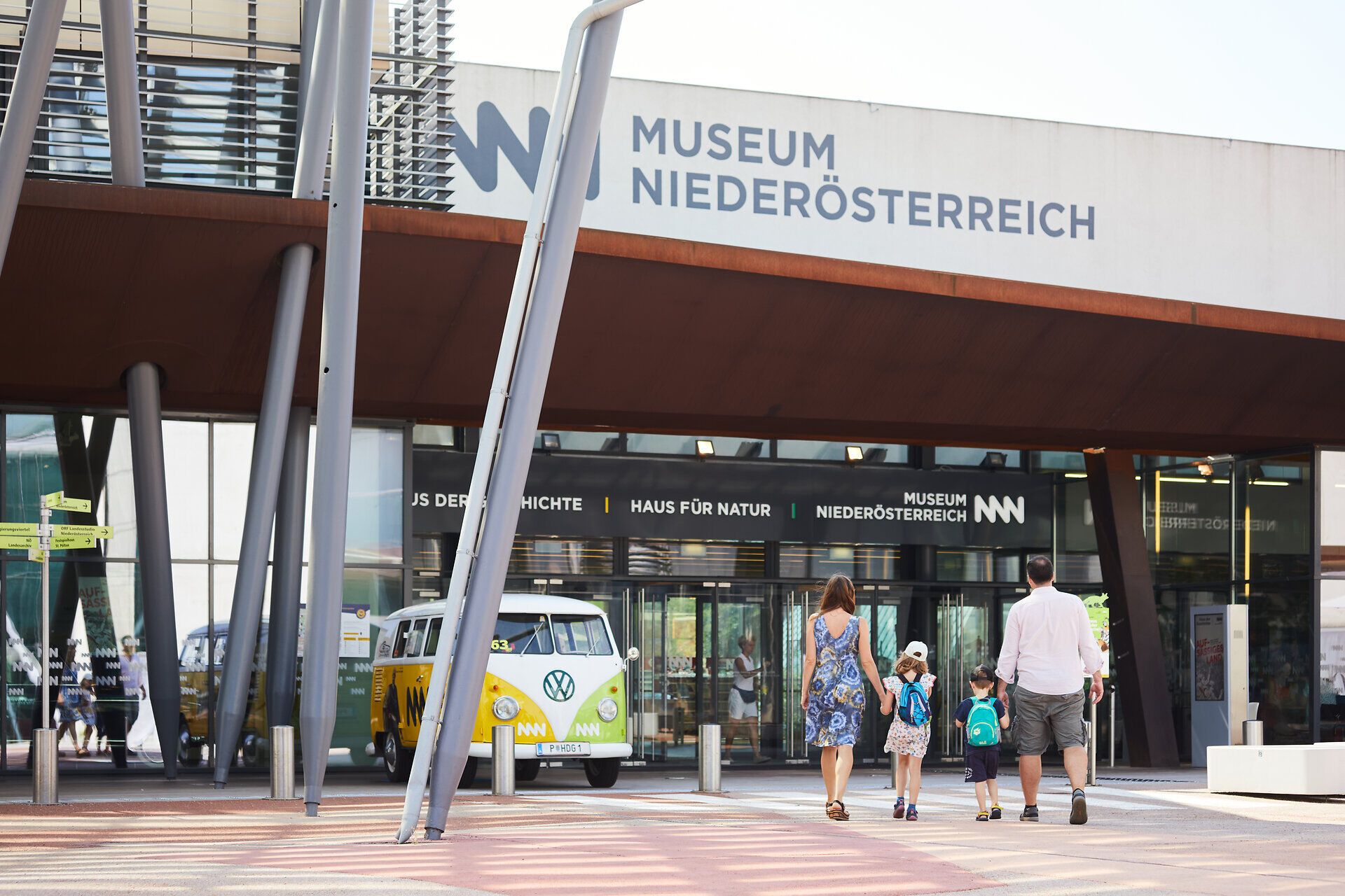Familien genießen einen sonnigen Tag vor dem modernen Museum, das mit seiner beeindruckenden Architektur begeistert. Die fröhlichen Gesichter der Besucher spiegeln die Vorfreude auf die spannenden Ausstellungen wider, die hier auf sie warten.