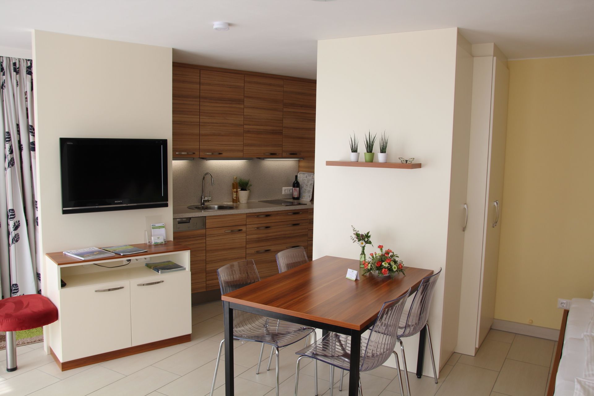 Modernes Gartenappartement mit Küche, Esstisch und Fernseher.