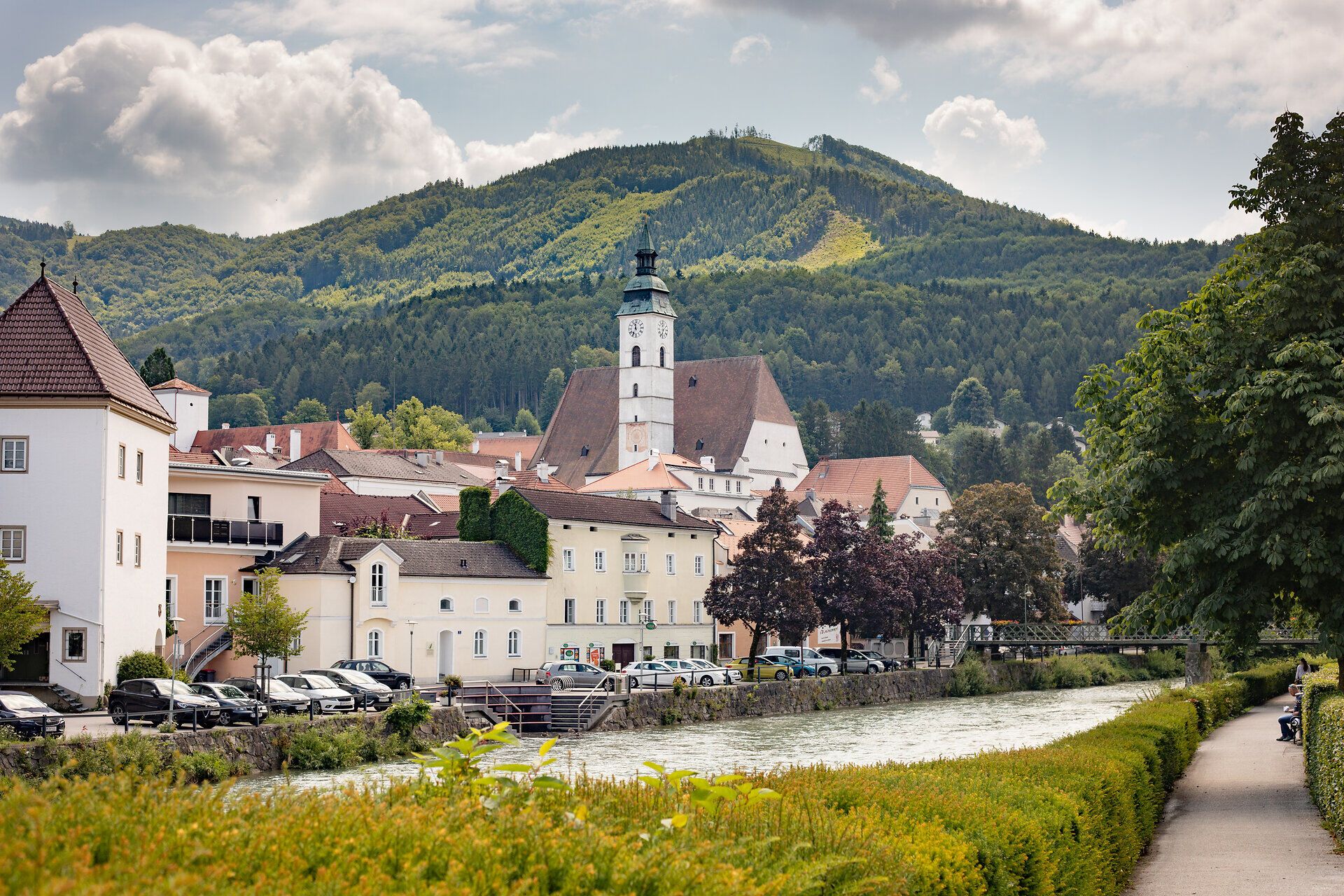 Die malerische Stadtansicht von Scheibbs im Sommer strahlt eine einladende Atmosphäre aus. Umgeben von sanften Hügeln und üppigem Grün, bietet der Blick auf die historischen Gebäude und die Kirche ein Gefühl von Ruhe und Harmonie. Ein perfekter Ort für Paare, die die Schönheit der Natur und die charmante Architektur genießen möchten.
