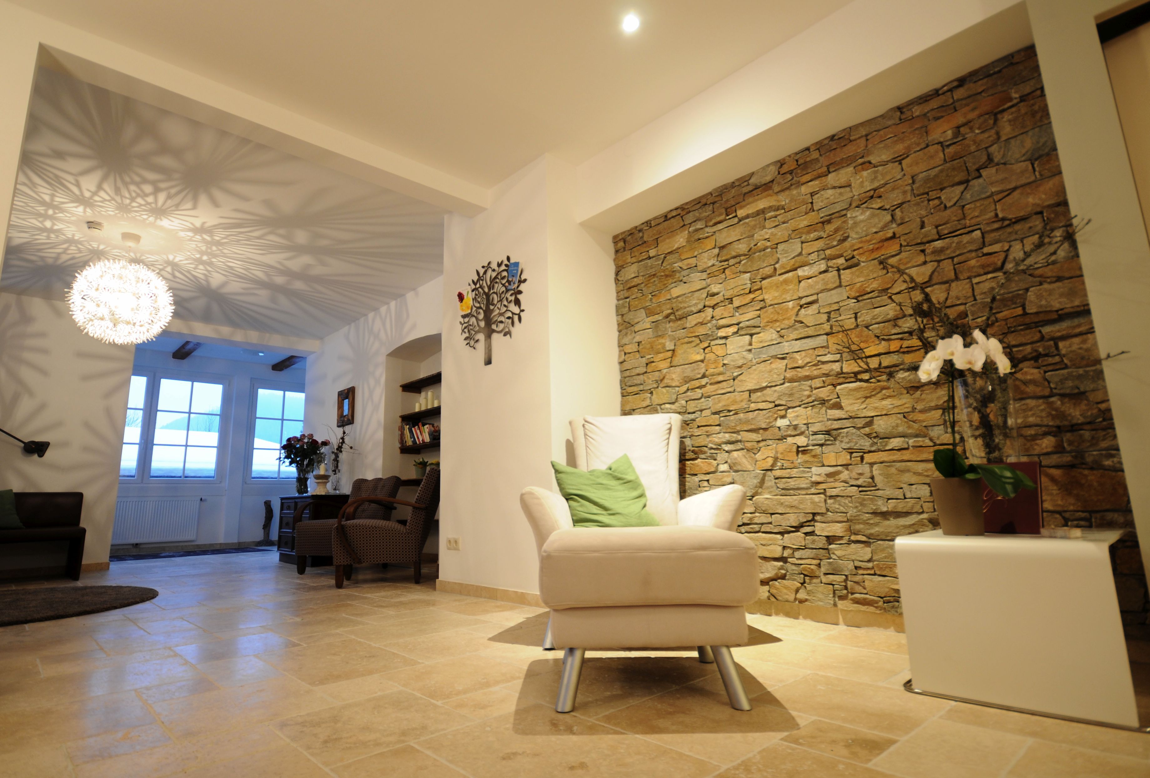 Gemütlicher Raum mit Steinwand, Sessel und dekorativer Lampe.