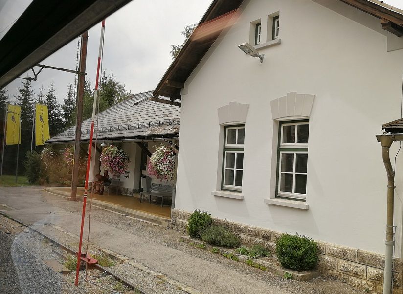 Bahnhof Mitterbach mit weißem Gebäude und Blumen.