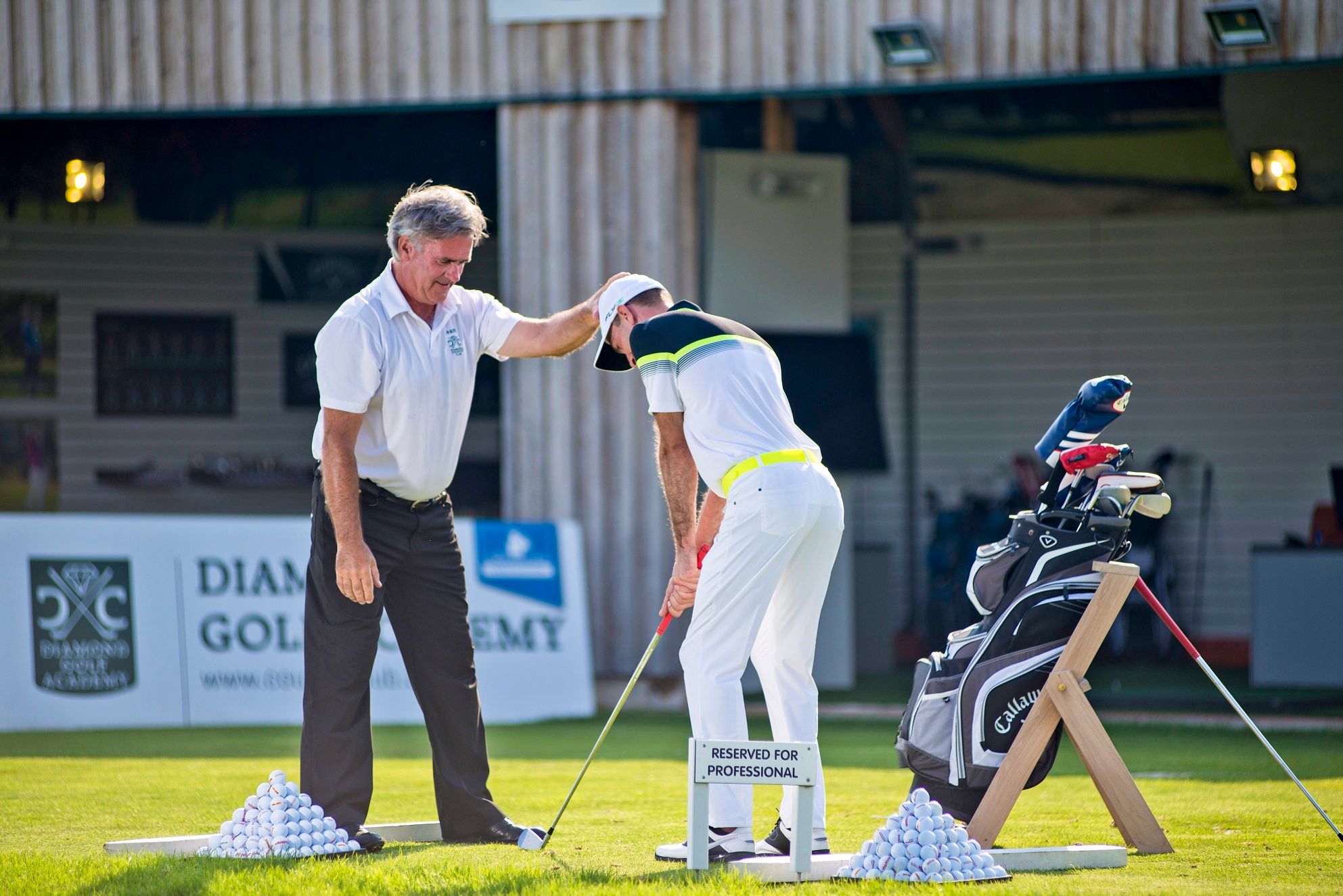 Ein Golflehrer gibt einem Schüler Anweisungen auf einem Übungsplatz der Diamond Golf Academy.