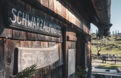 Holzschild „Schwarzalmhütte“ an der Außenfassade.