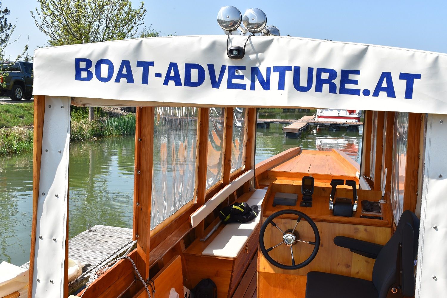 Innenansicht eines Bootes mit Steuer und Sitz, beschriftet mit 'Boat-Adventure.at'.