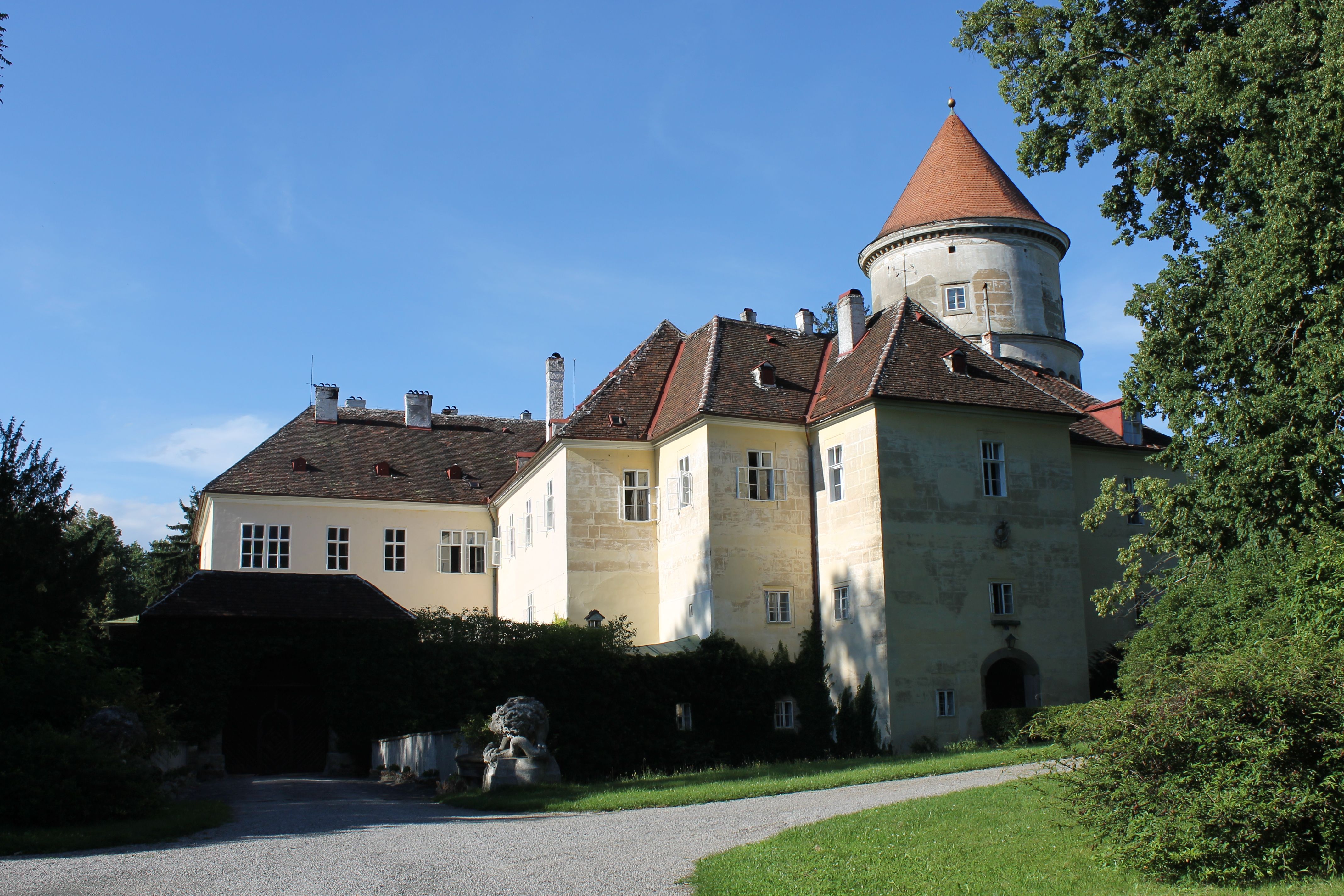 Schloss in Pyhra mit Turm und Garten bei sonnigem Wetter.