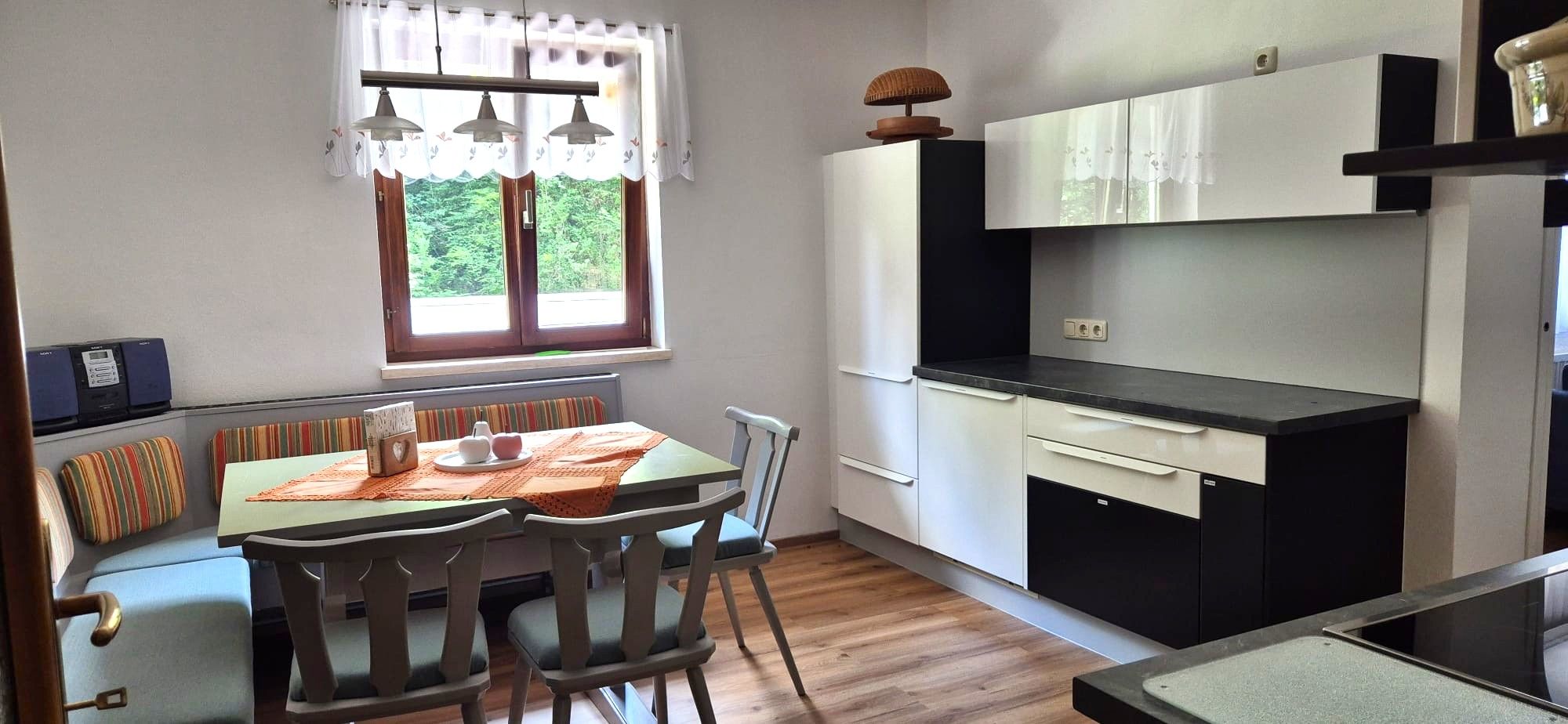 Küche mit Esstisch und Stühlen, Fenster mit Blick ins Grüne.