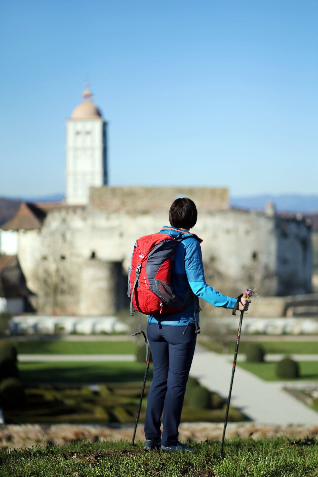 Ein Wanderer genießt die atemberaubende Aussicht auf die majestätische Schallaburg, während die sanften Hügel des Melker Alpenvorlands im Hintergrund leuchten. Die klare Luft und die ruhige Umgebung laden dazu ein, die Schönheit der Natur in vollen Zügen zu erleben.