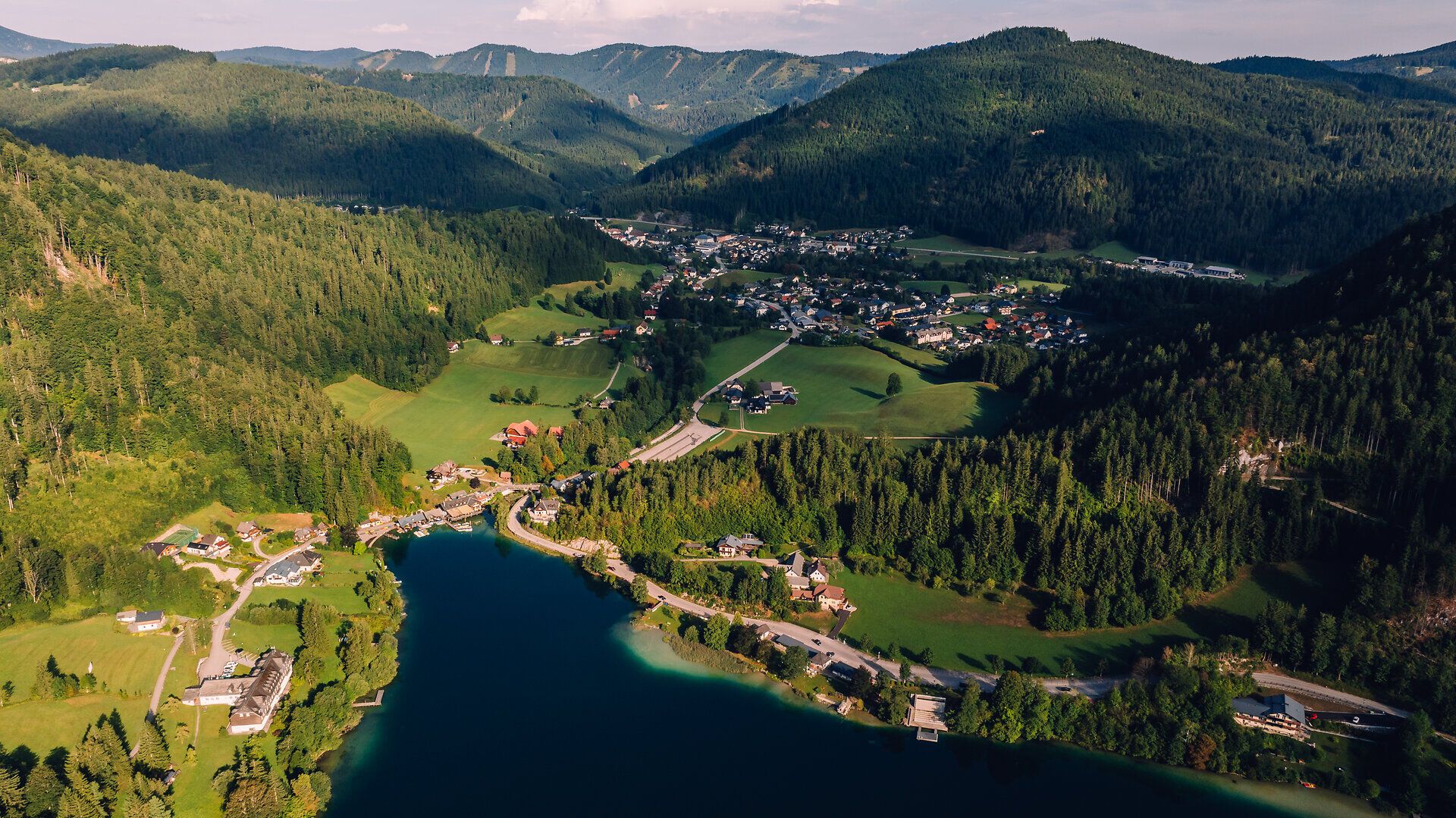 Drohnenaufnahme von Lunz am See mit dem Ortszentrum, dem Lunzer See und der umliegenden Berglandschaft.