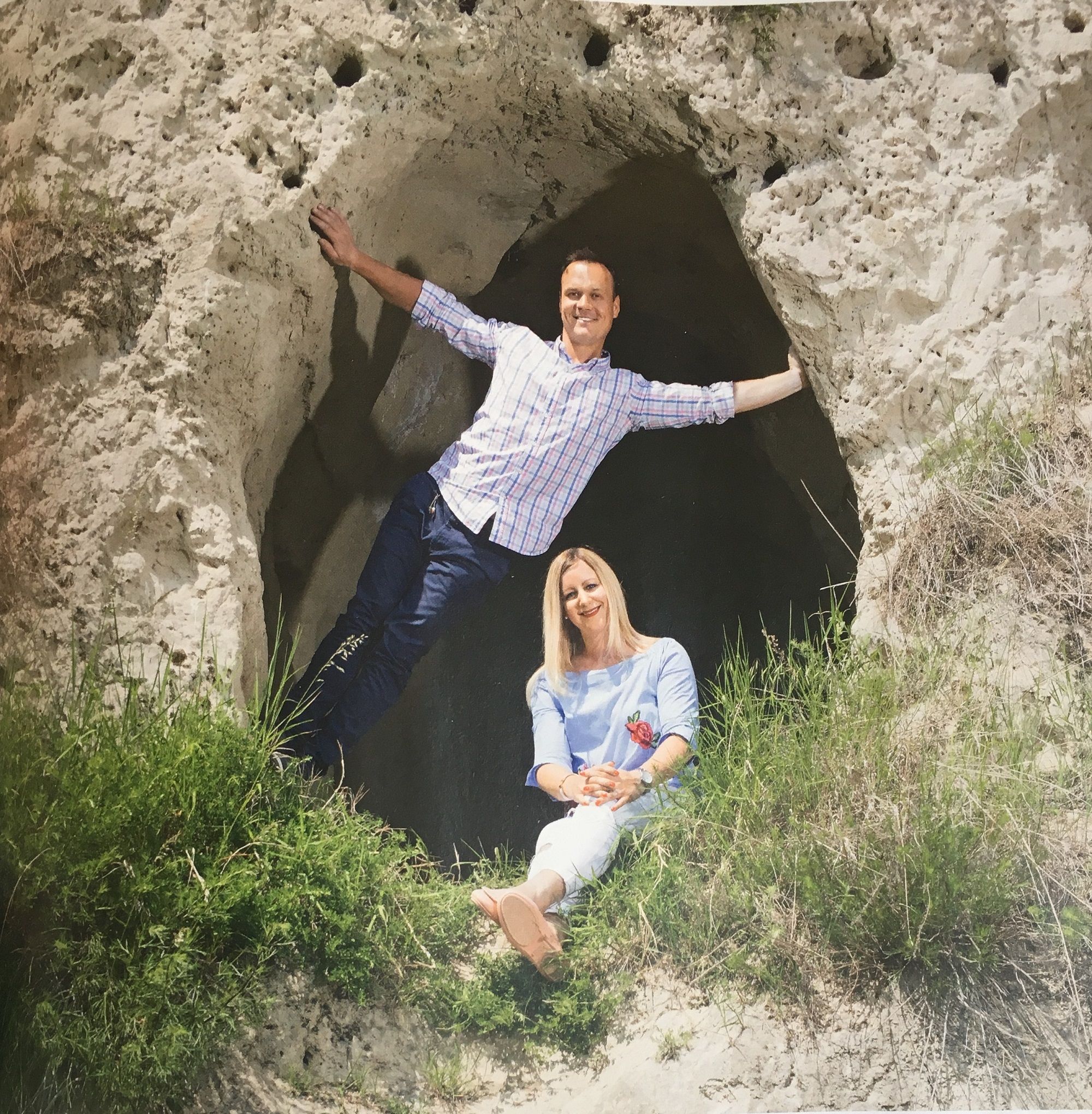Zwei Personen posieren vor einer Felsenhöhle.