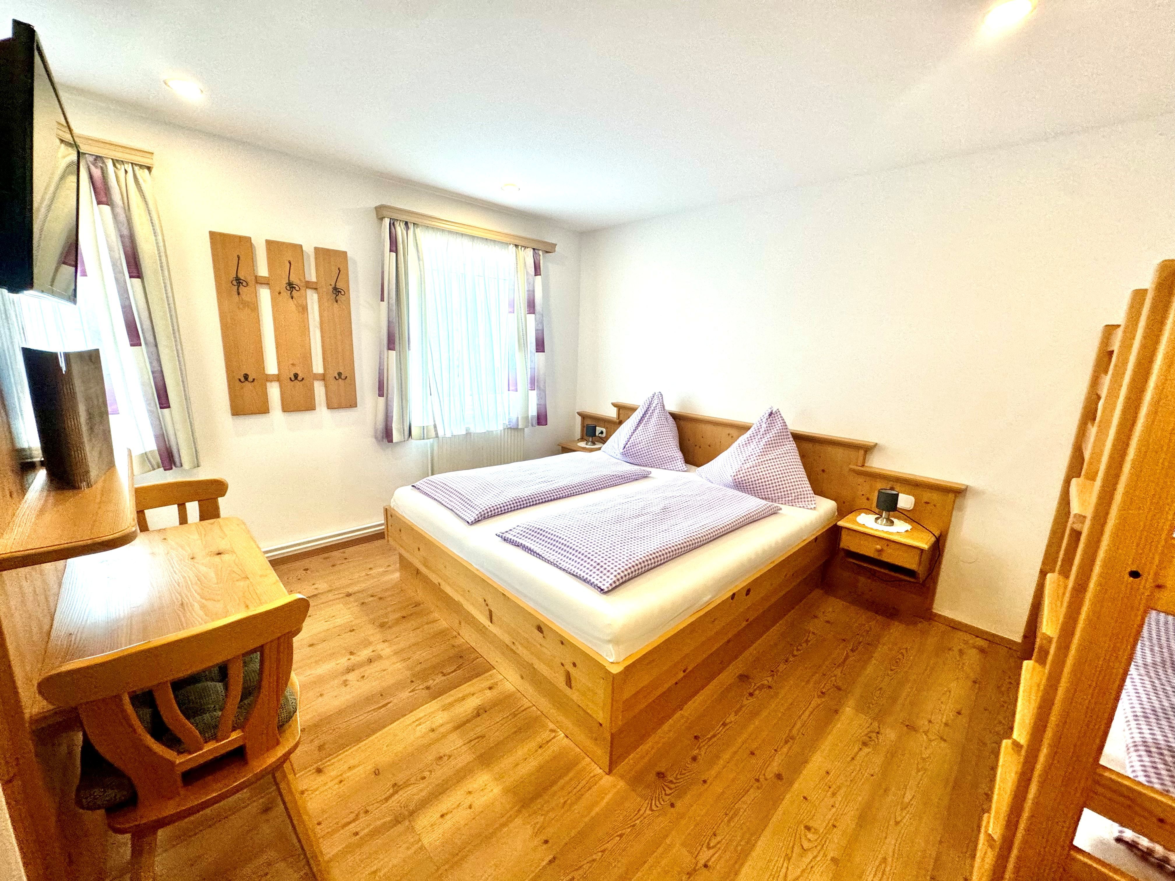 Ein gemütliches Schlafzimmer mit Holzmöbeln, einem Doppelbett und einem Etagenbett.