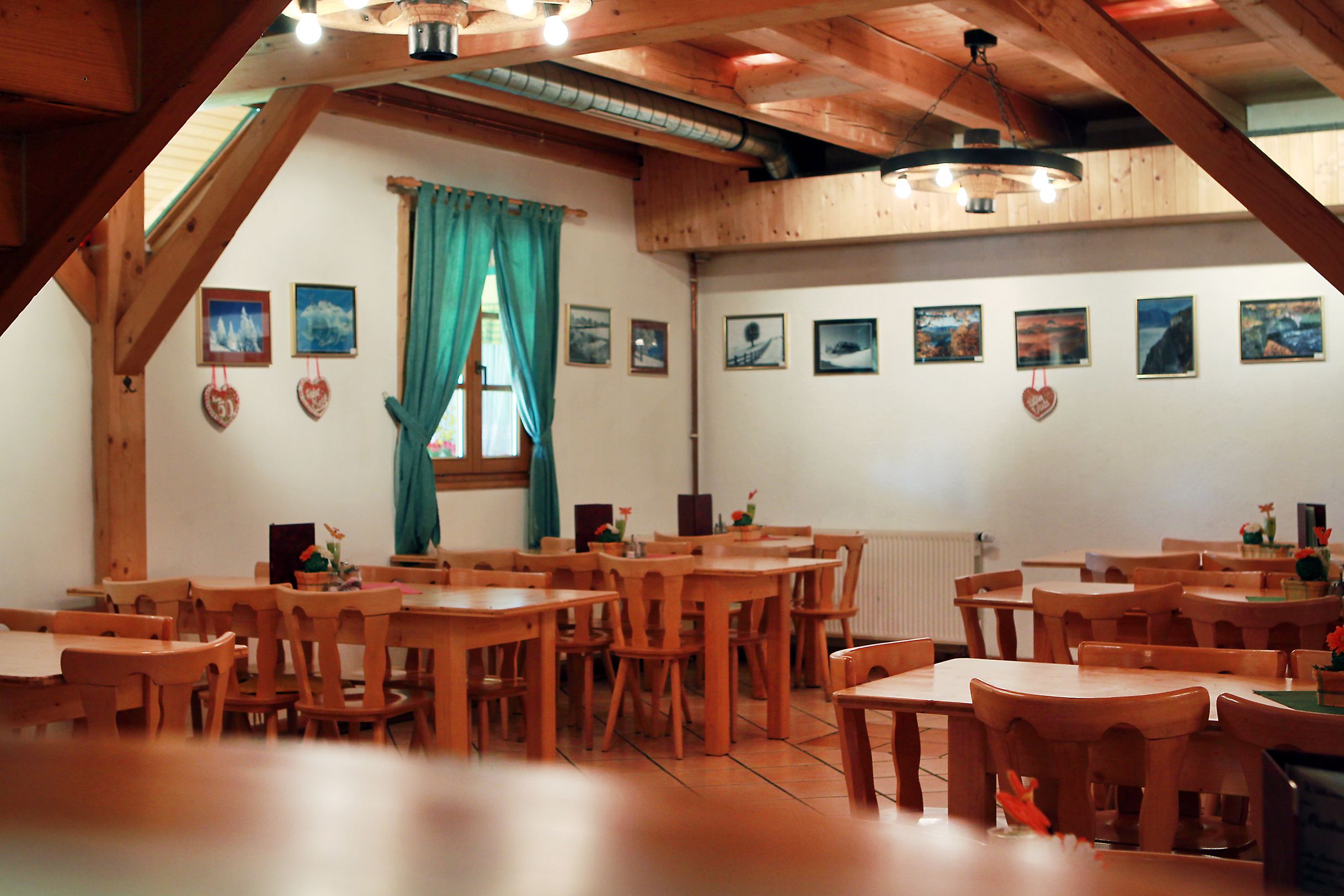 Innenansicht eines rustikalen Gastraums mit Holzmöbeln und Bildern an der Wand.