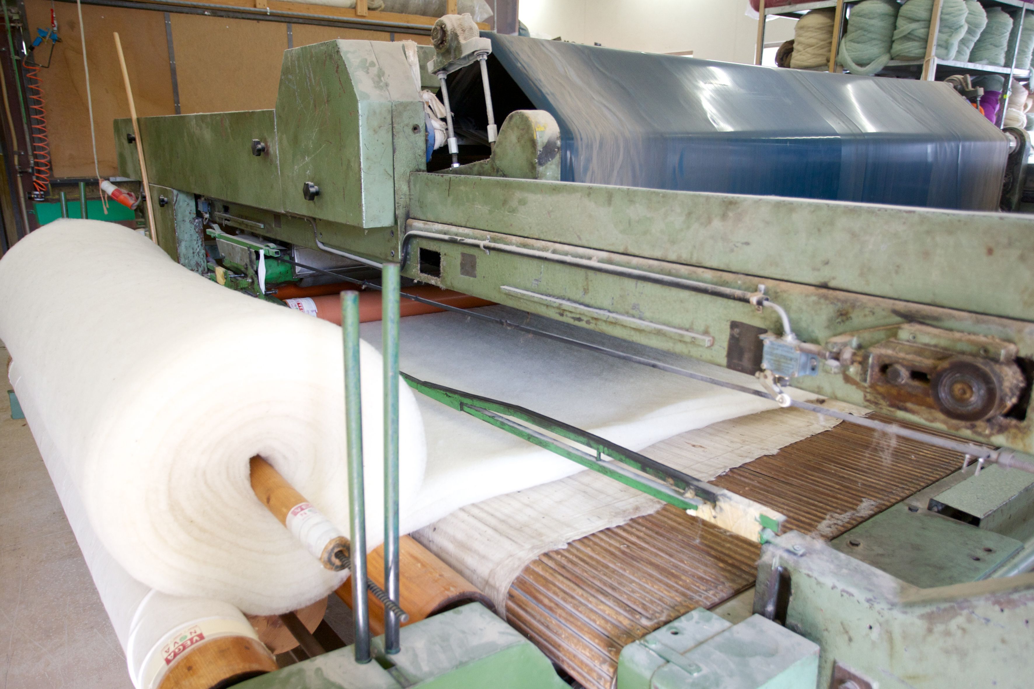 Maschine in einer Wollwerkstatt mit großen Rollen aus weißem Wollmaterial.