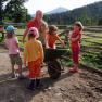 Children playing with a wheelbarrow on a farm.