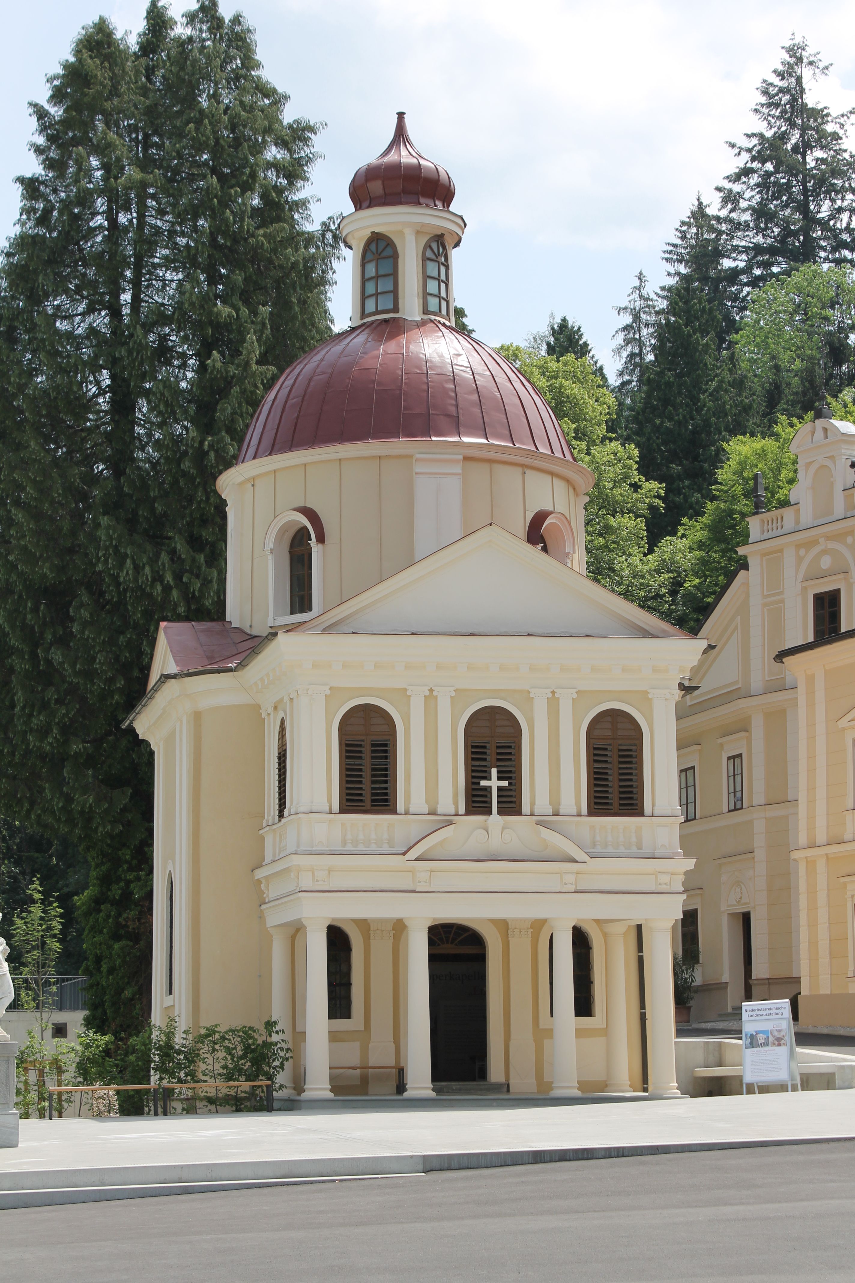 Die Töpperkapelle in Neubruck mit ihrer markanten Kuppel und klassizistischen Architektur, umgeben von Bäumen.