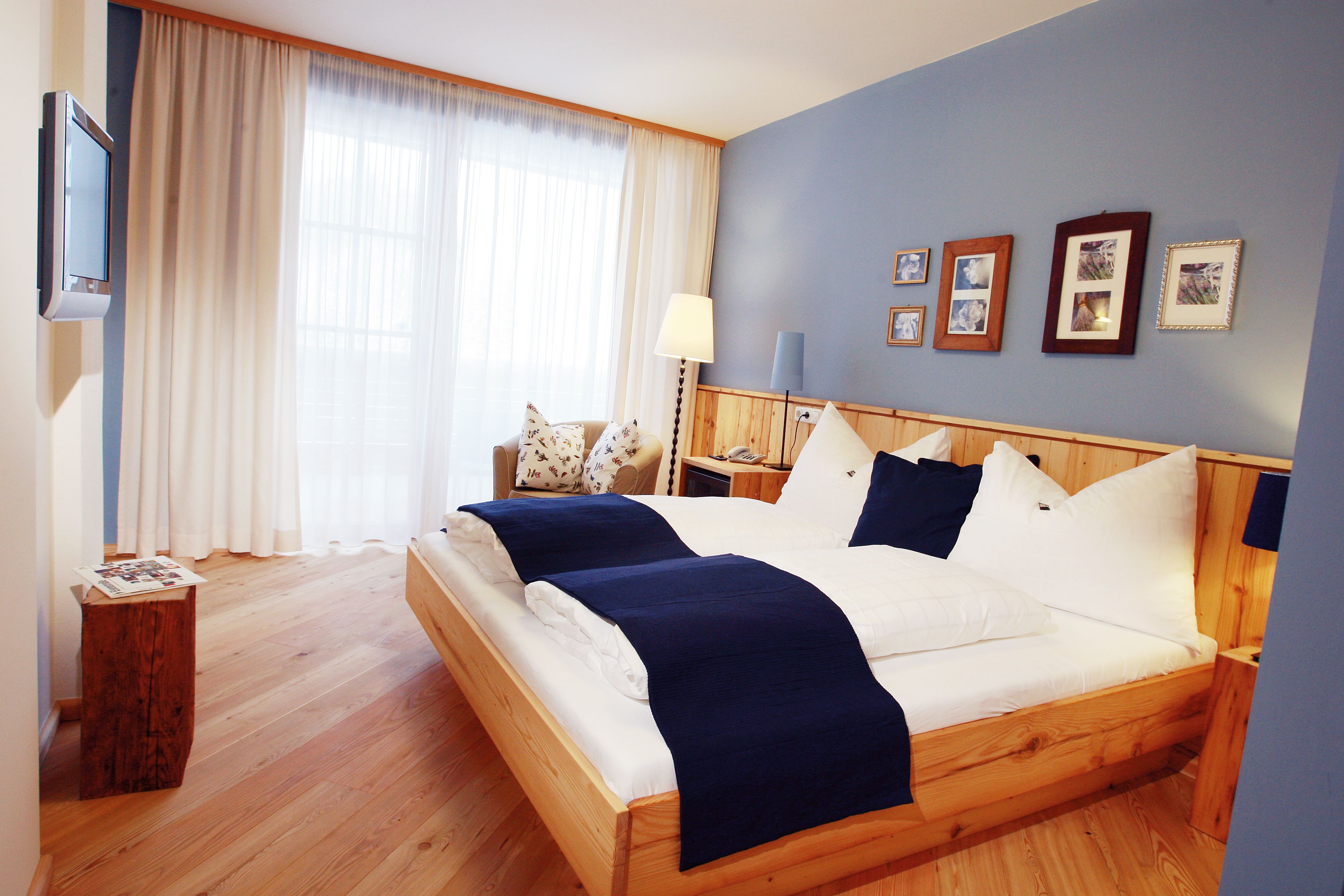 Gemütliches Hotelzimmer mit Doppelbett, blauen Akzenten und Holzmöbeln.
