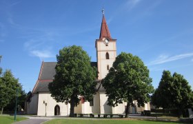 Pfarrkirche Pyhra mit Turm und Bäumen im Vordergrund.