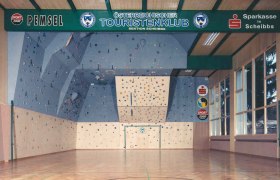 Interior view of a climbing hall with a blue climbing wall and colorful holds.
