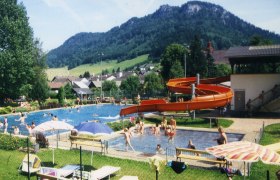 Outdoor pool with slide and mountain landscape in the background.