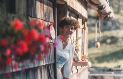 Frau blickt aus Eingangstür einer rustikalen Almhütte.