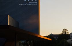 Im warmen Licht der Abendsonne strahlt das moderne Gebäude des Museums in sanften Grautönen. Die ruhige Atmosphäre lädt dazu ein, die Umgebung zu erkunden und die Schönheit der Architektur zu genießen. Ein Ort, der sowohl Kultur als auch Natur harmonisch vereint.