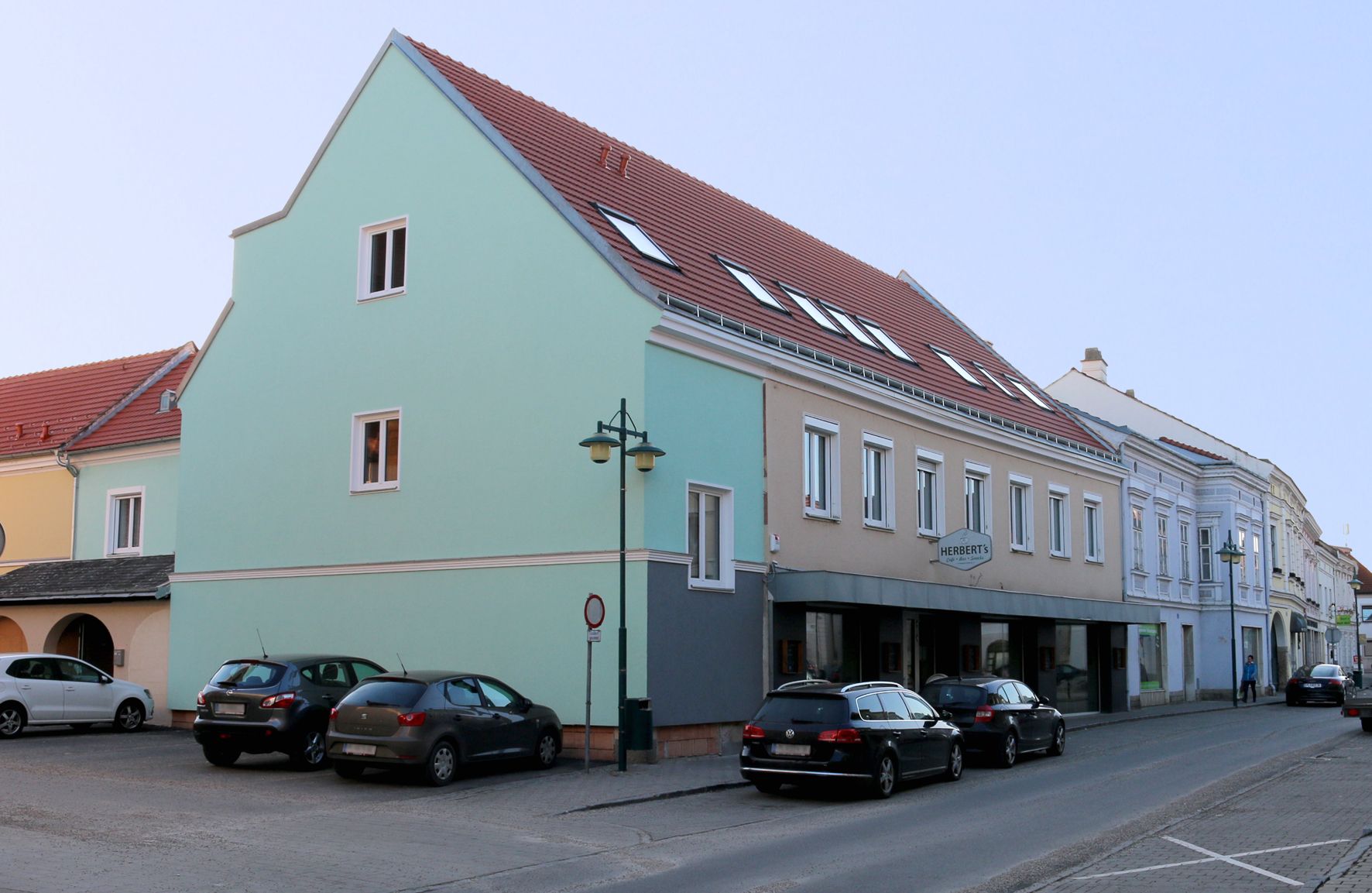 Straßenszene in Traismauer mit mehrstöckigem Gebäude und parkenden Autos.