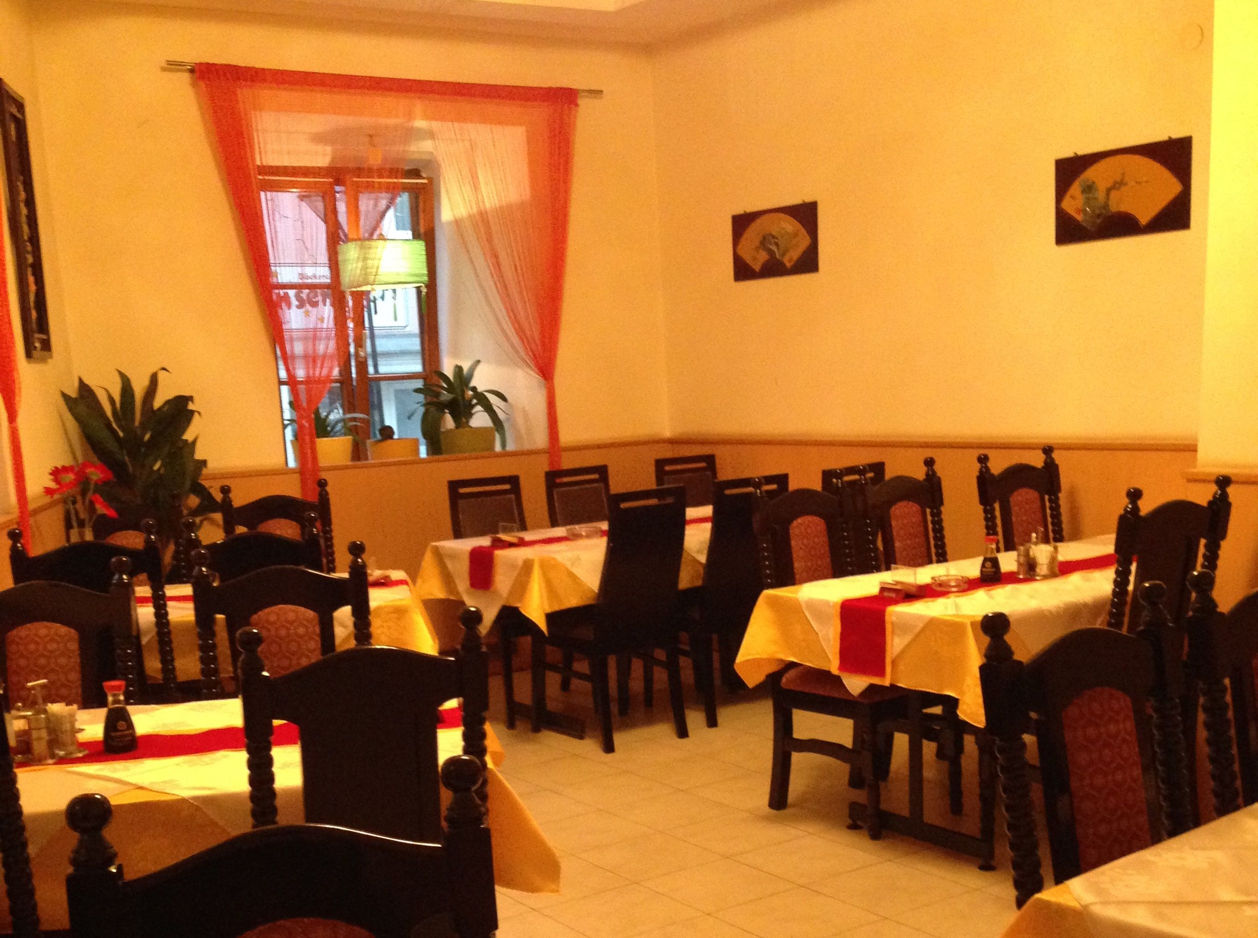 Innenansicht eines asiatischen Restaurants mit gedeckten Tischen und Stühlen.