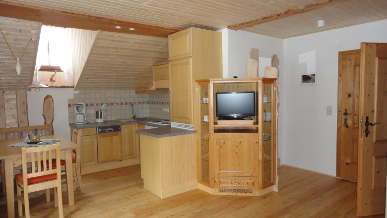 Gem&uuml;tliche Dachgeschosswohnung mit Holzm&ouml;beln, K&uuml;chenzeile und Esstisch.