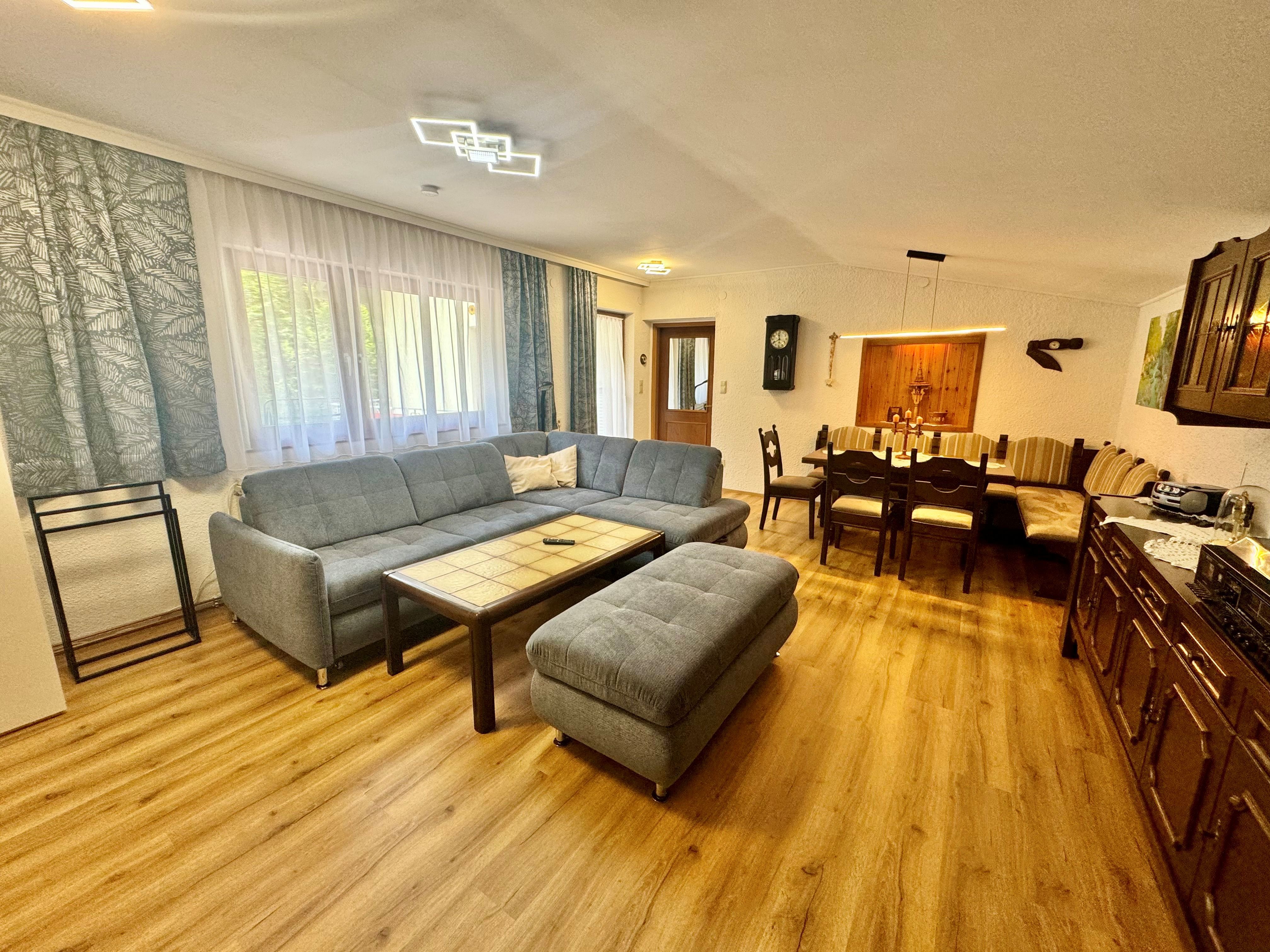 Wohnzimmer einer Ferienwohnung mit blauem Sofa und einer zusätzlichen Eckbank mit Tisch