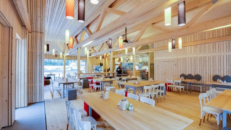 Interior view of a modern restaurant with wooden furniture and colorful hanging lamps.