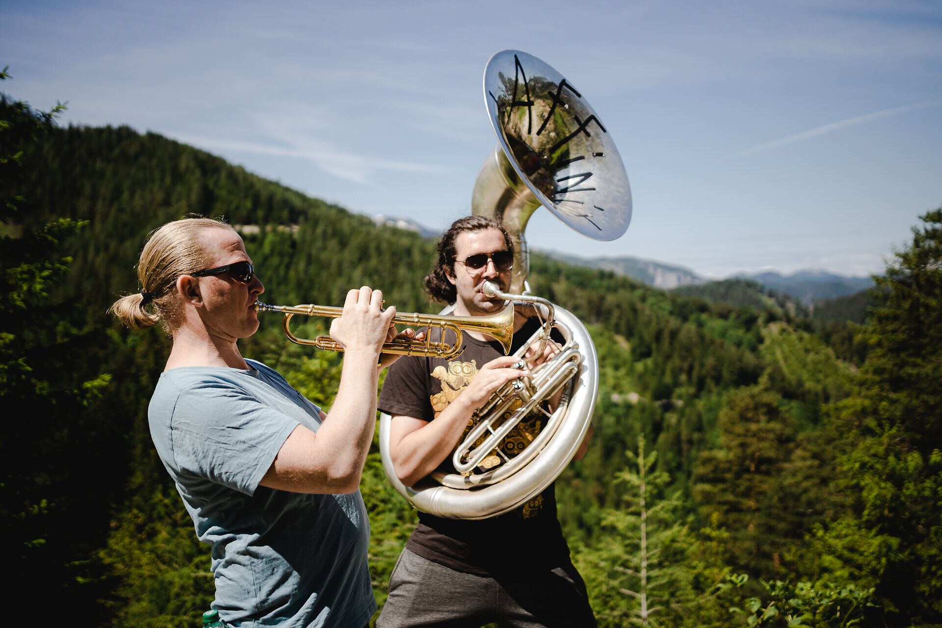 Inmitten der majestätischen Berge erklingen die kraftvollen Klänge von Trompete und Tuba, während die Musiker die frische Morgenluft genießen. Die atemberaubende Kulisse der Natur schafft eine harmonische Verbindung zwischen Musik und Landschaft, die jeden Besucher verzaubert.