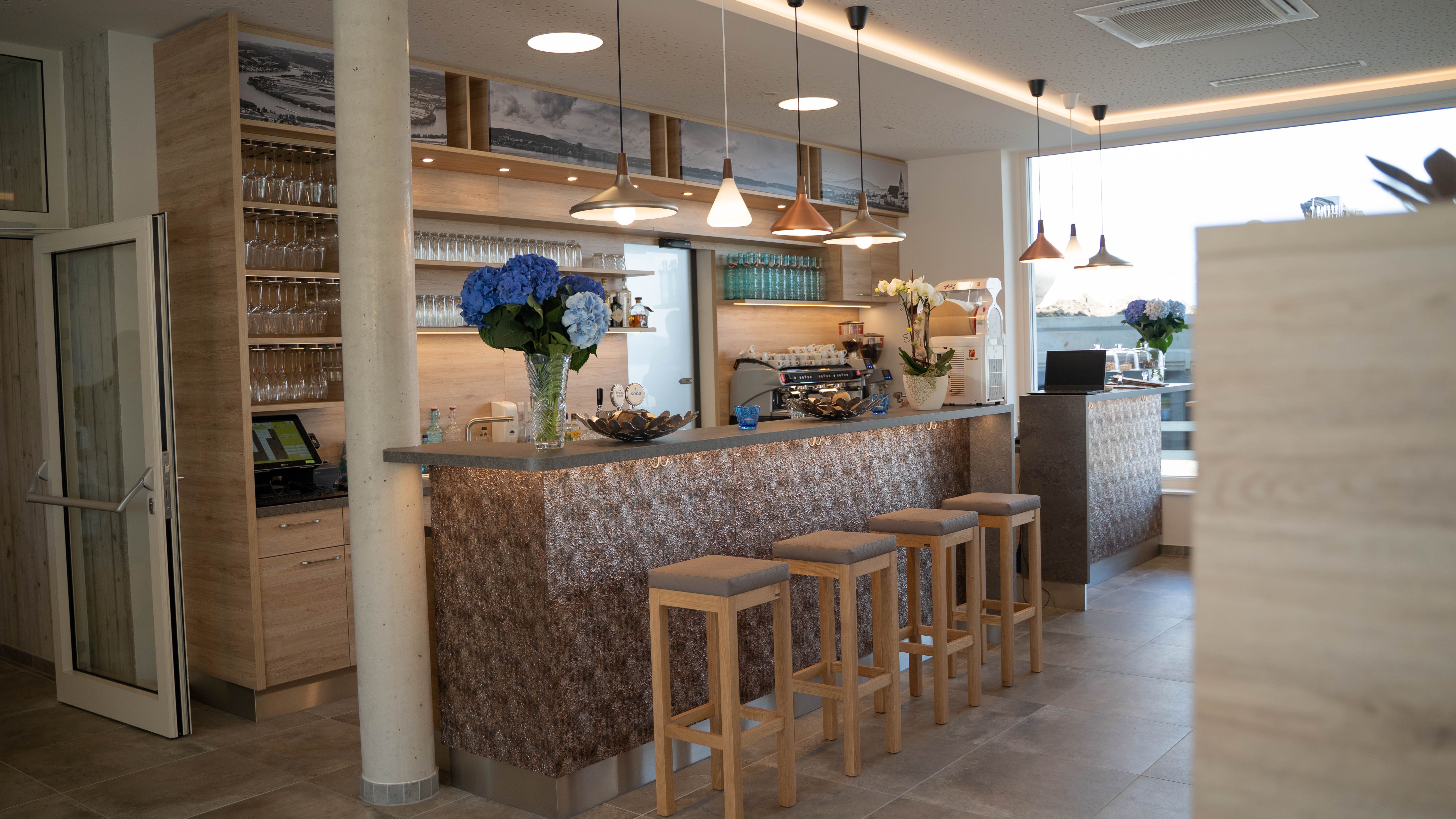 Moderne Bar mit Holzdekor, Barhockern und Blumen.