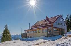 Umgeben von schneebedeckten Bergen strahlt das Annaberger Haus eine einladende Wärme aus. Die klare Winterluft und die strahlende Sonne schaffen eine perfekte Kulisse für Skitouren und entspannte Momente in der Natur.