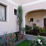 Inner courtyard with a view of a pink fa&ccedil;ade and many potted plants and windows.